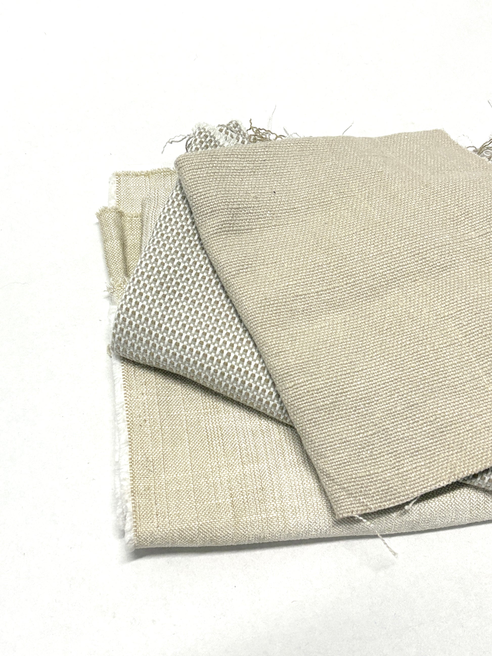 Stack of three neutral coloured heavyweight fabrics, texture visible