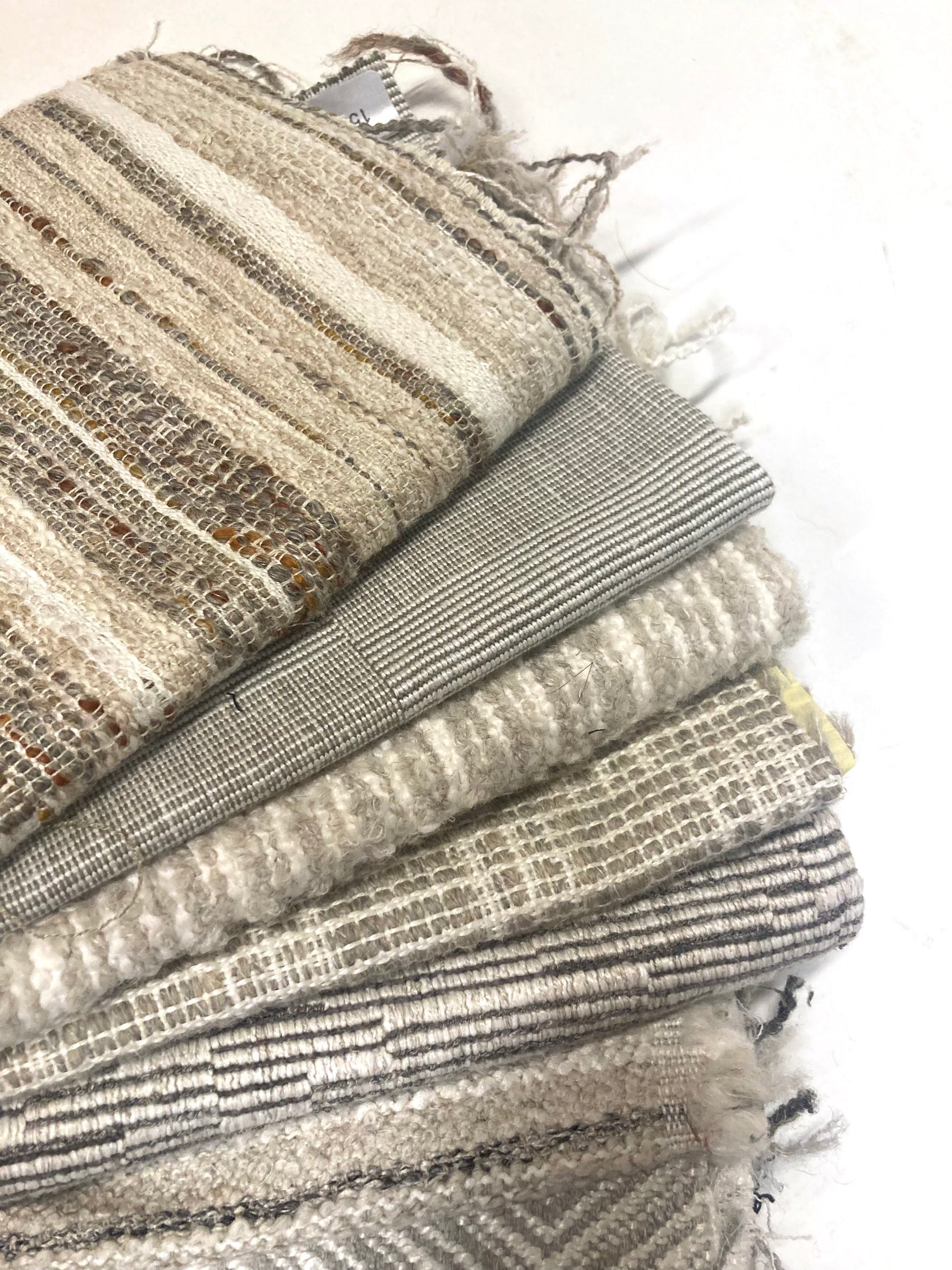 Close-up of several neutral coloured heavyweight fabric, texture visible