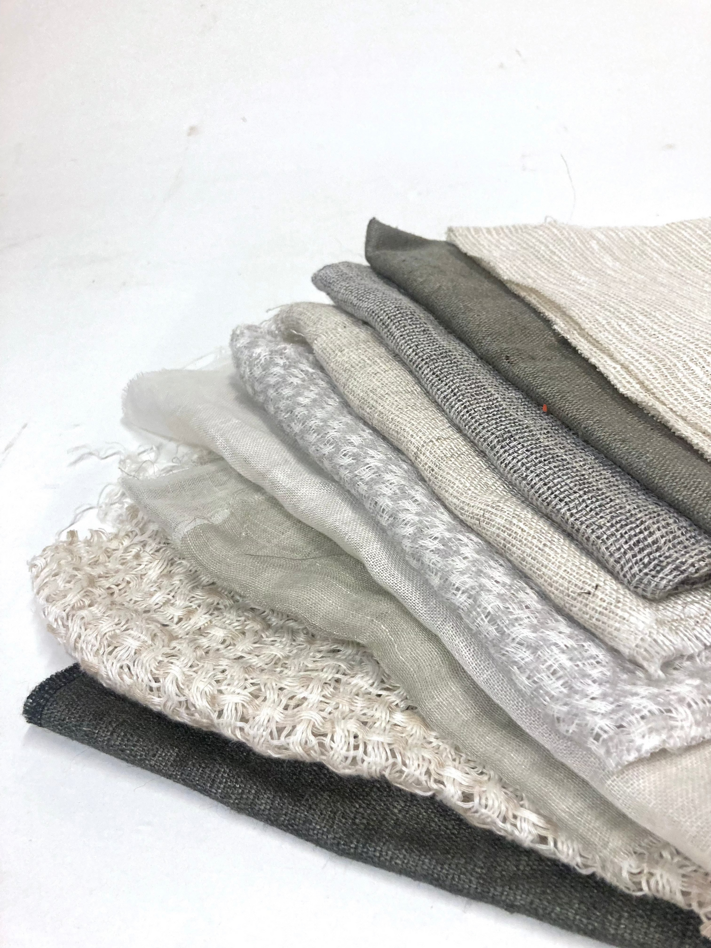 A stack of various sized neutral coloured lightweight fabric, texture visible 