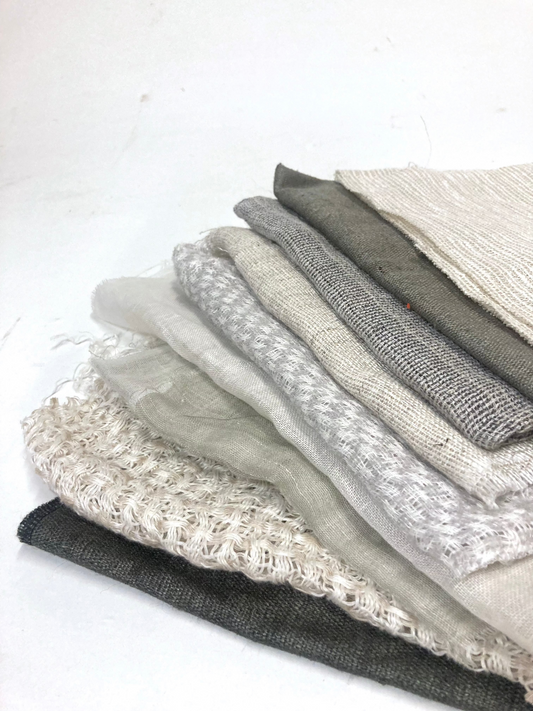 A stack of various sized neutral coloured lightweight fabric, texture visible 