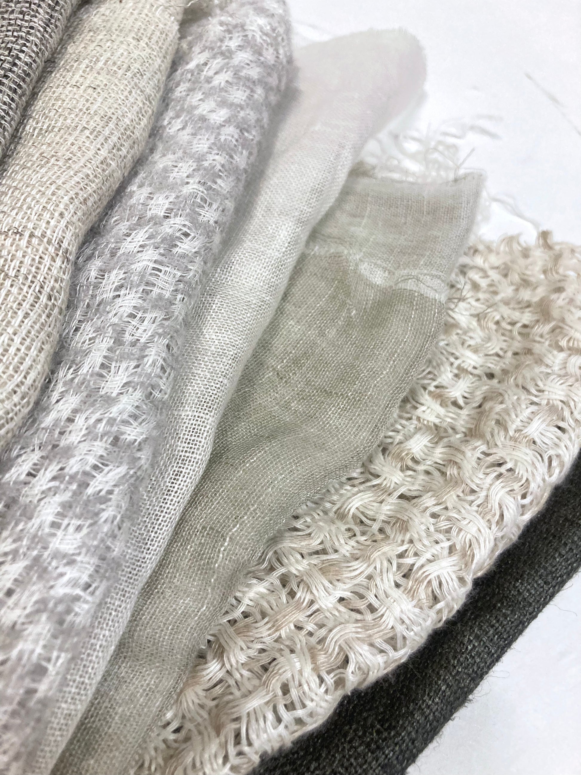 Close-up of a stack of various sized neutral coloured lightweight fabric, texture visible 