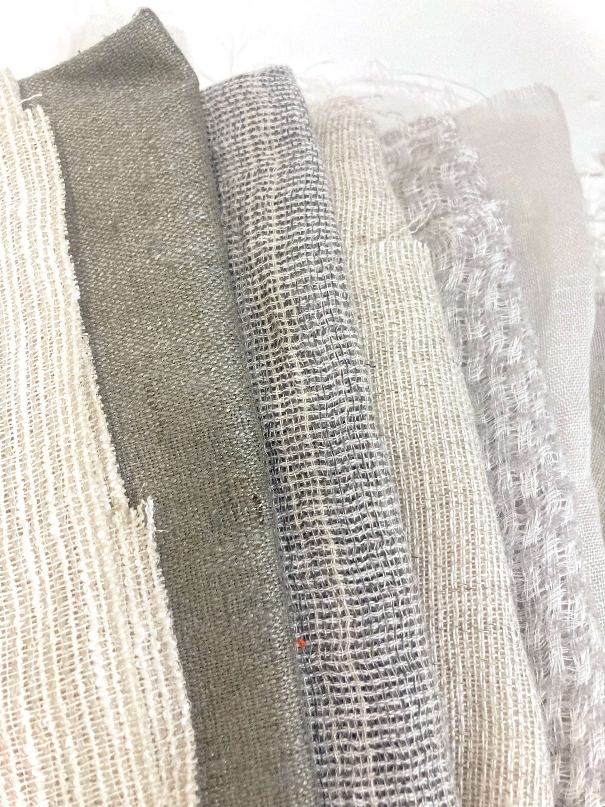 Close-up of a stack of various sized neutral coloured lightweight fabric, texture visible 