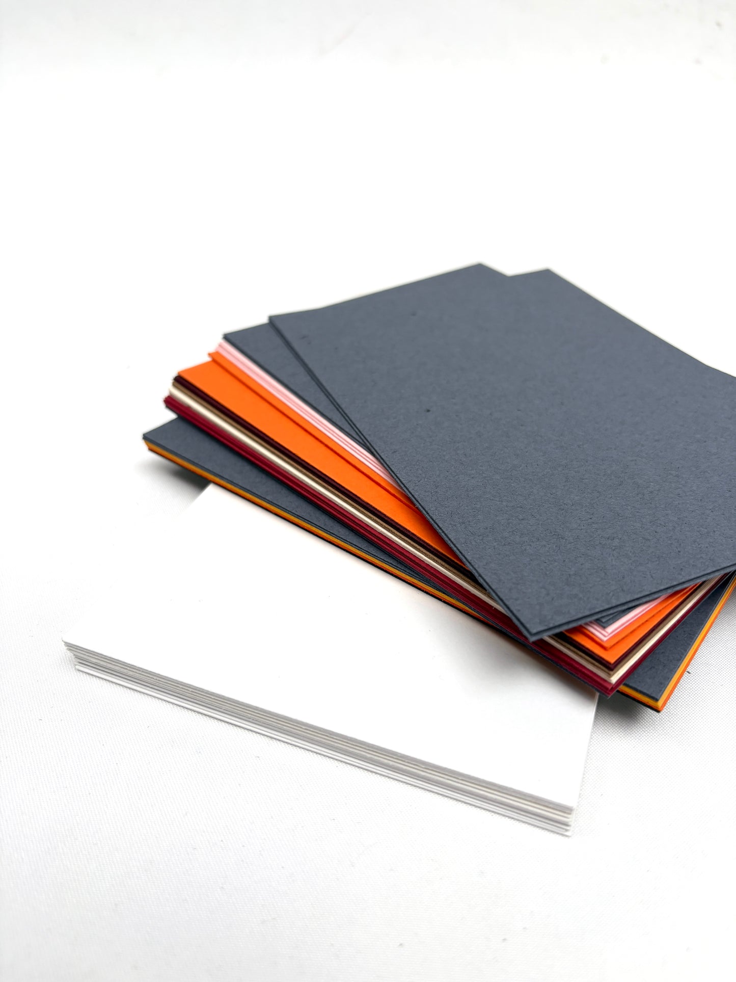 A stack of various coloured papers and a stack white papers 