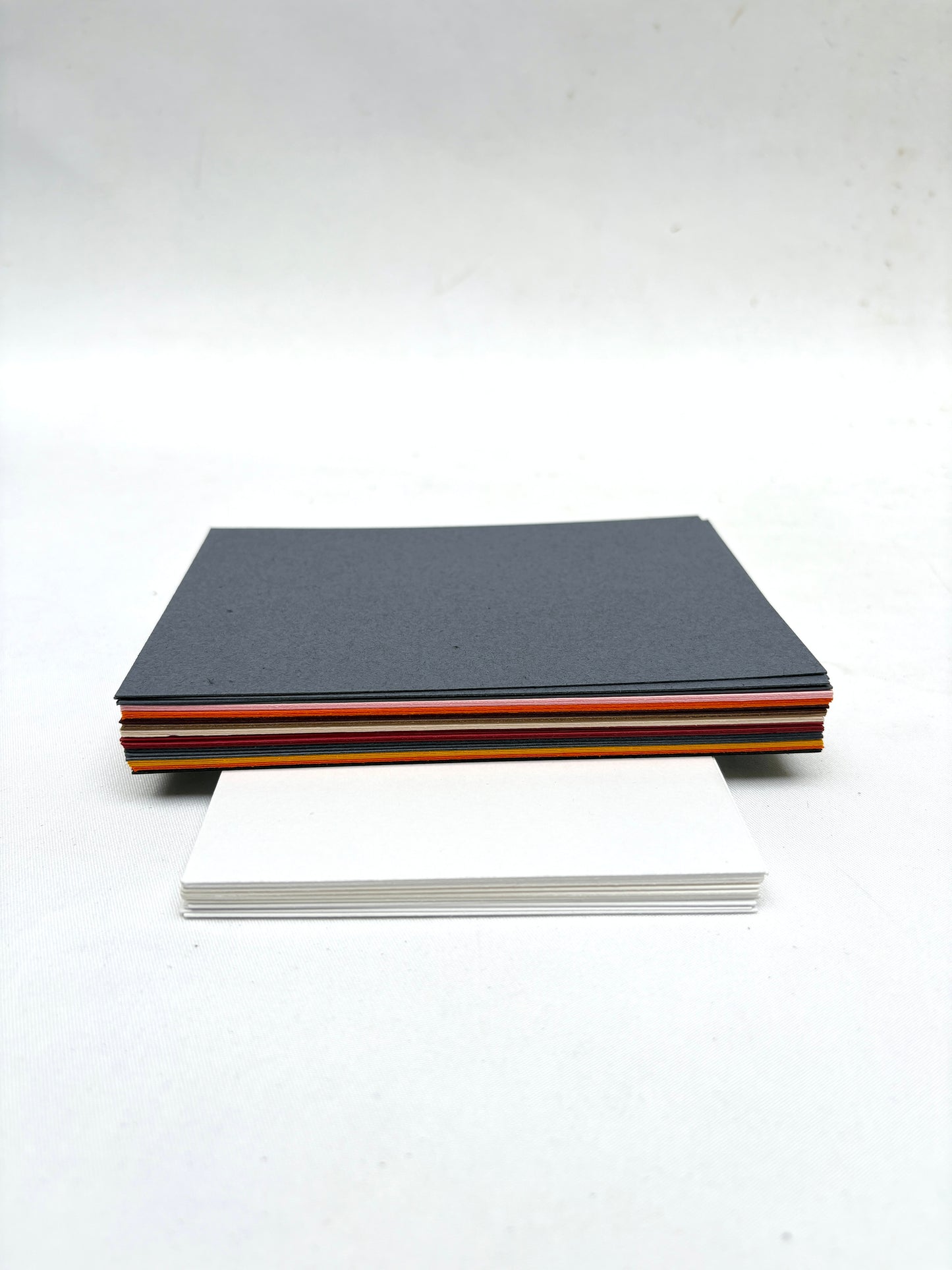 A stack of various coloured papers and a stack white papers 