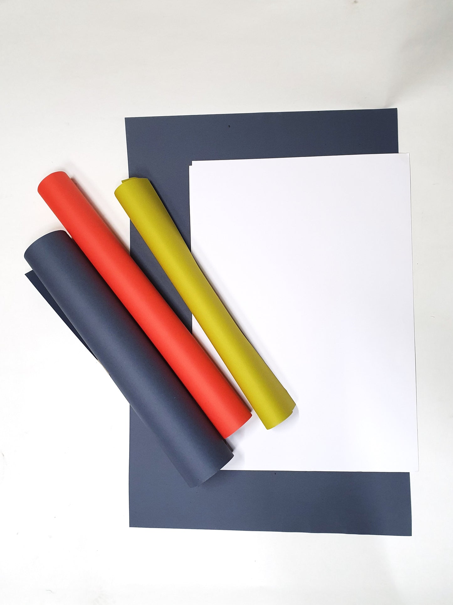 A collection of rolled coloured papers and unfolded papers with various sizes 
