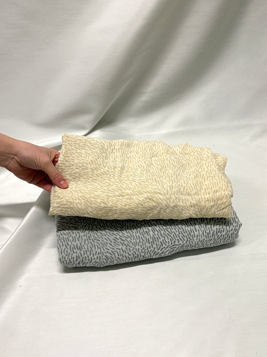 A stack of patterned cotton fabric with light brown and light black