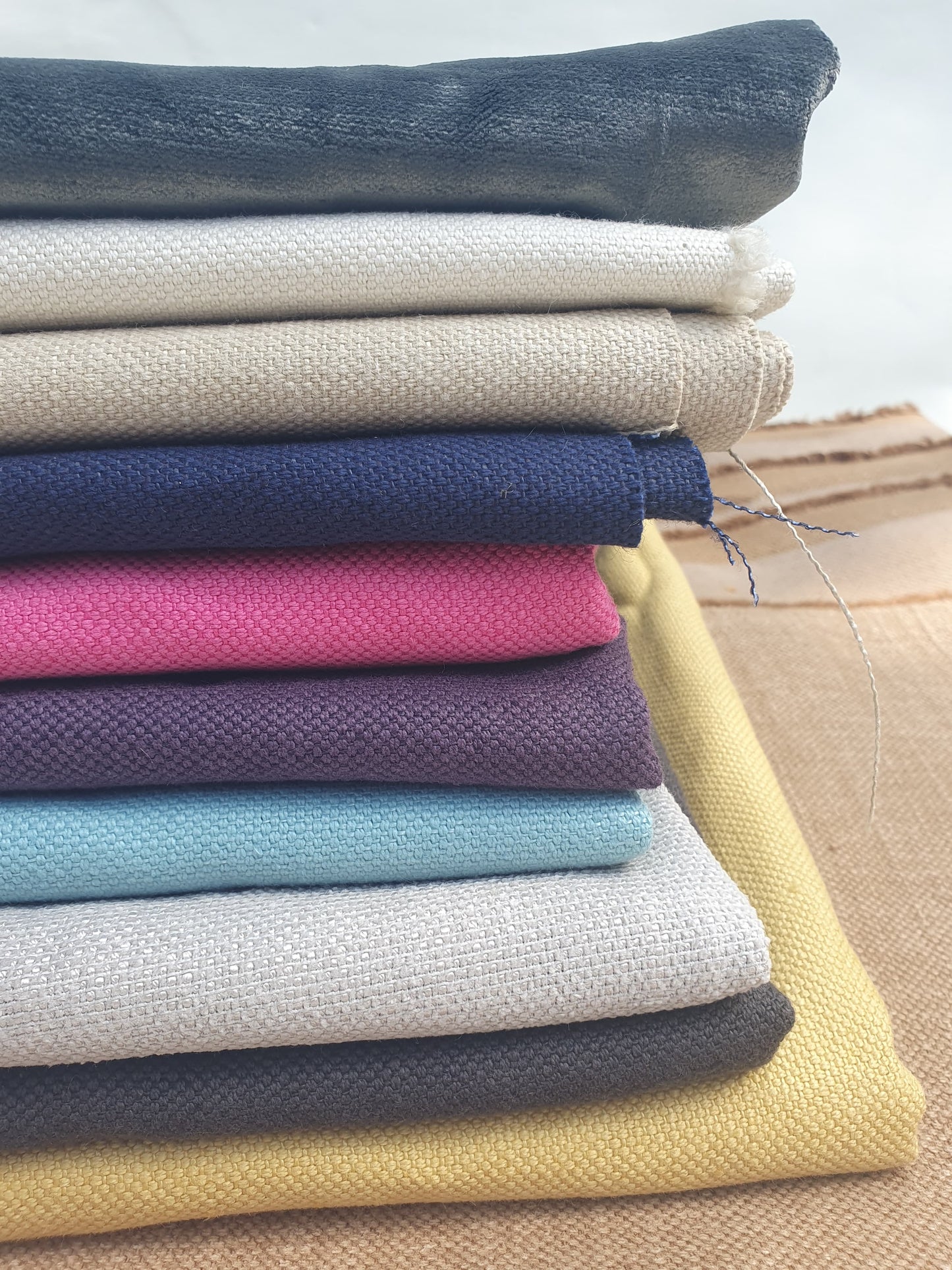 Close-up of a stack of various coloured plain fabrics 