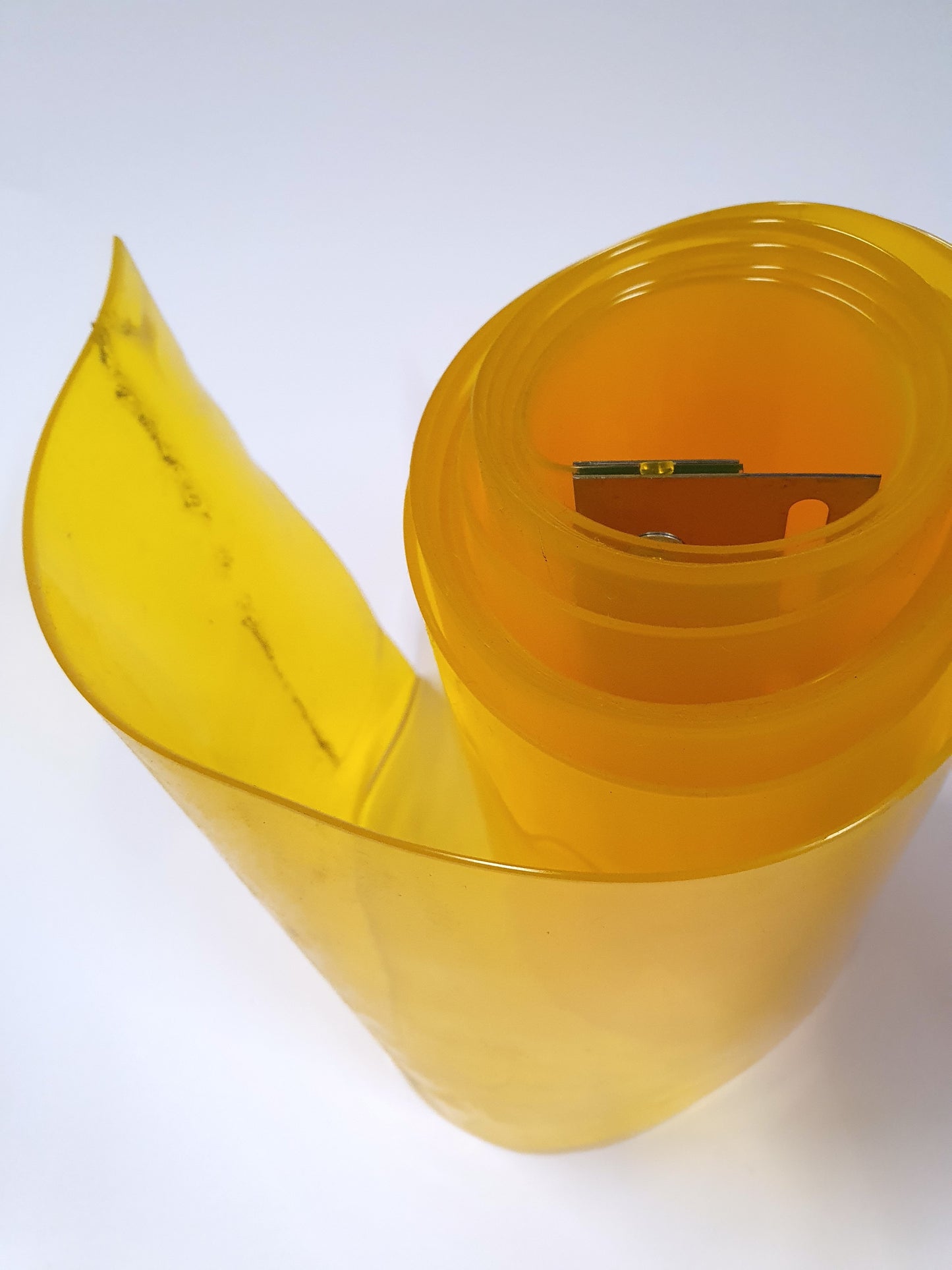 A rolled up yellow PVC strip curtain with a metal hanger attached. 