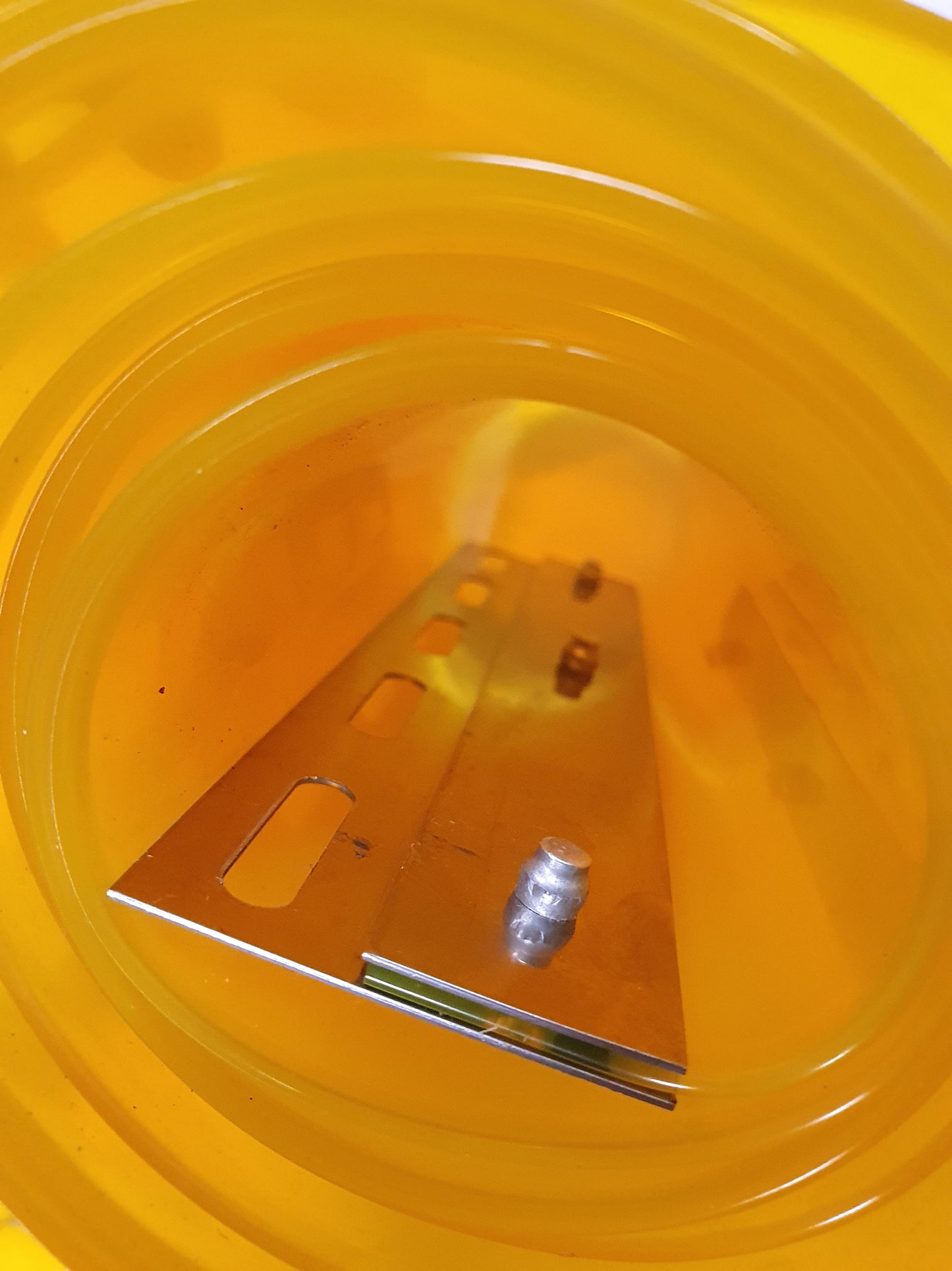 Close-up of a rolled up yellow PVC strip curtain with a metal hanger attached. 