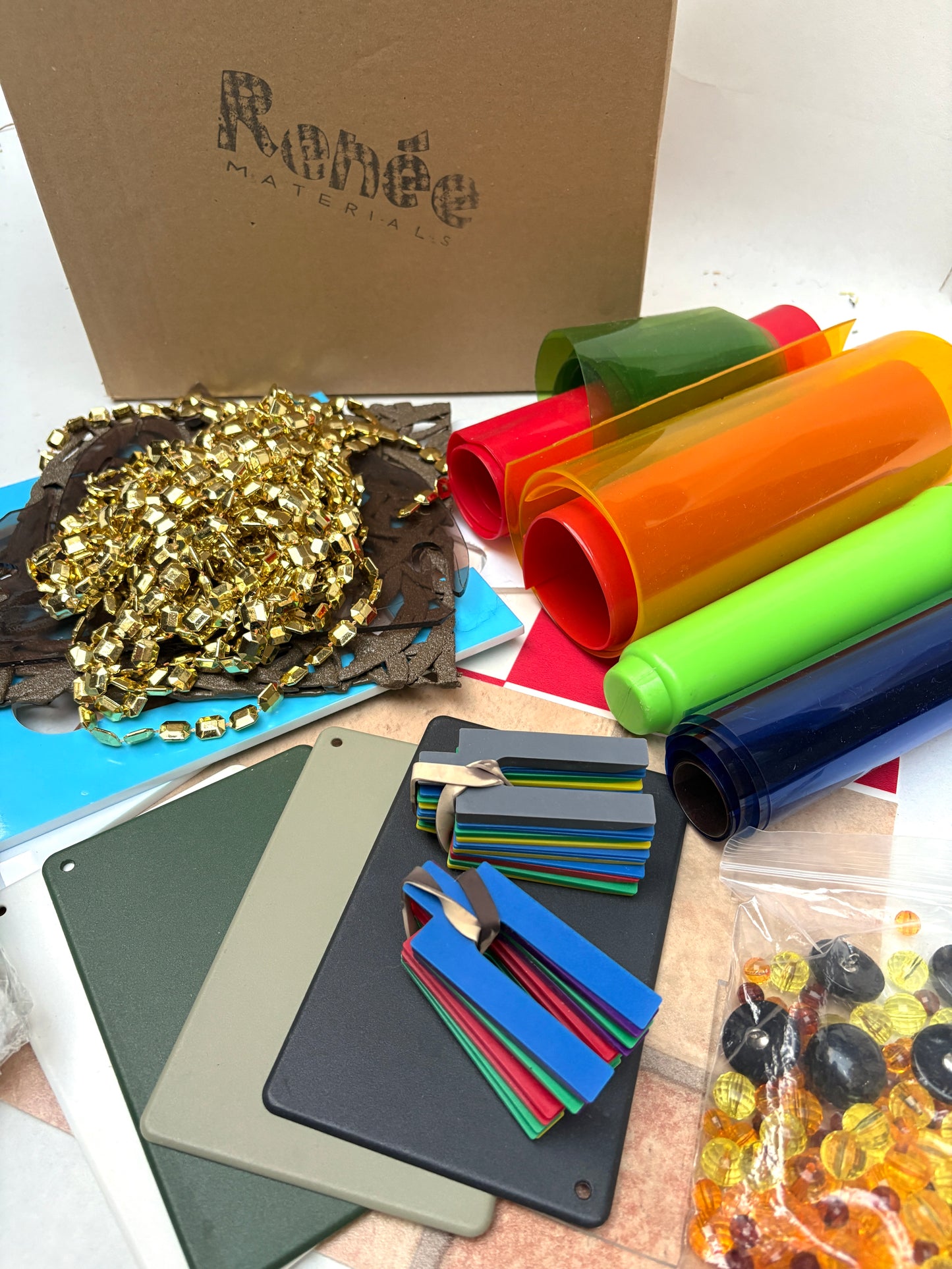 Collection of colourful plastic materials including PVC, tiles, buttons, and decorative items