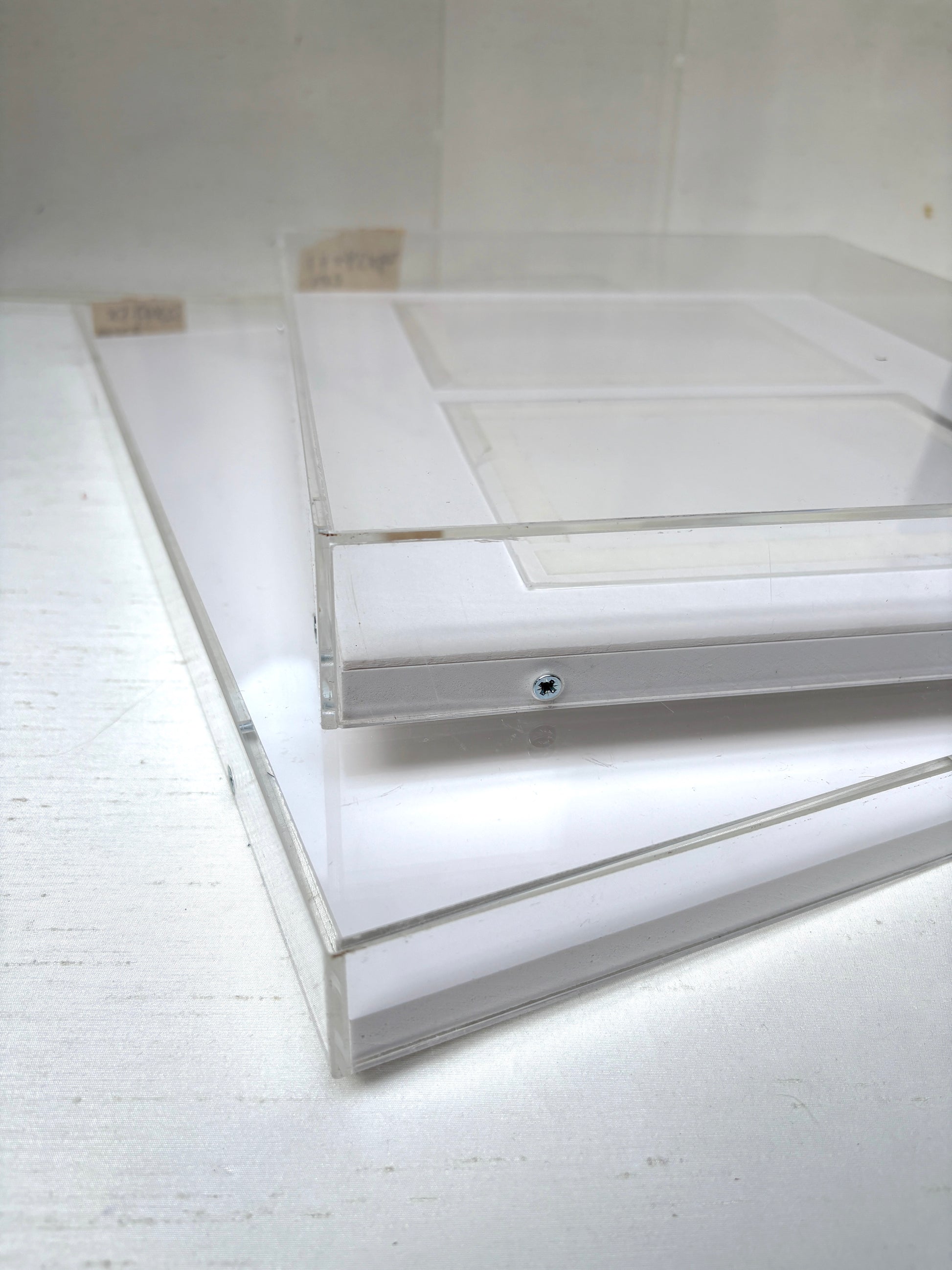 Close-up of 2 clear rectangular perspex frames with white panels inside