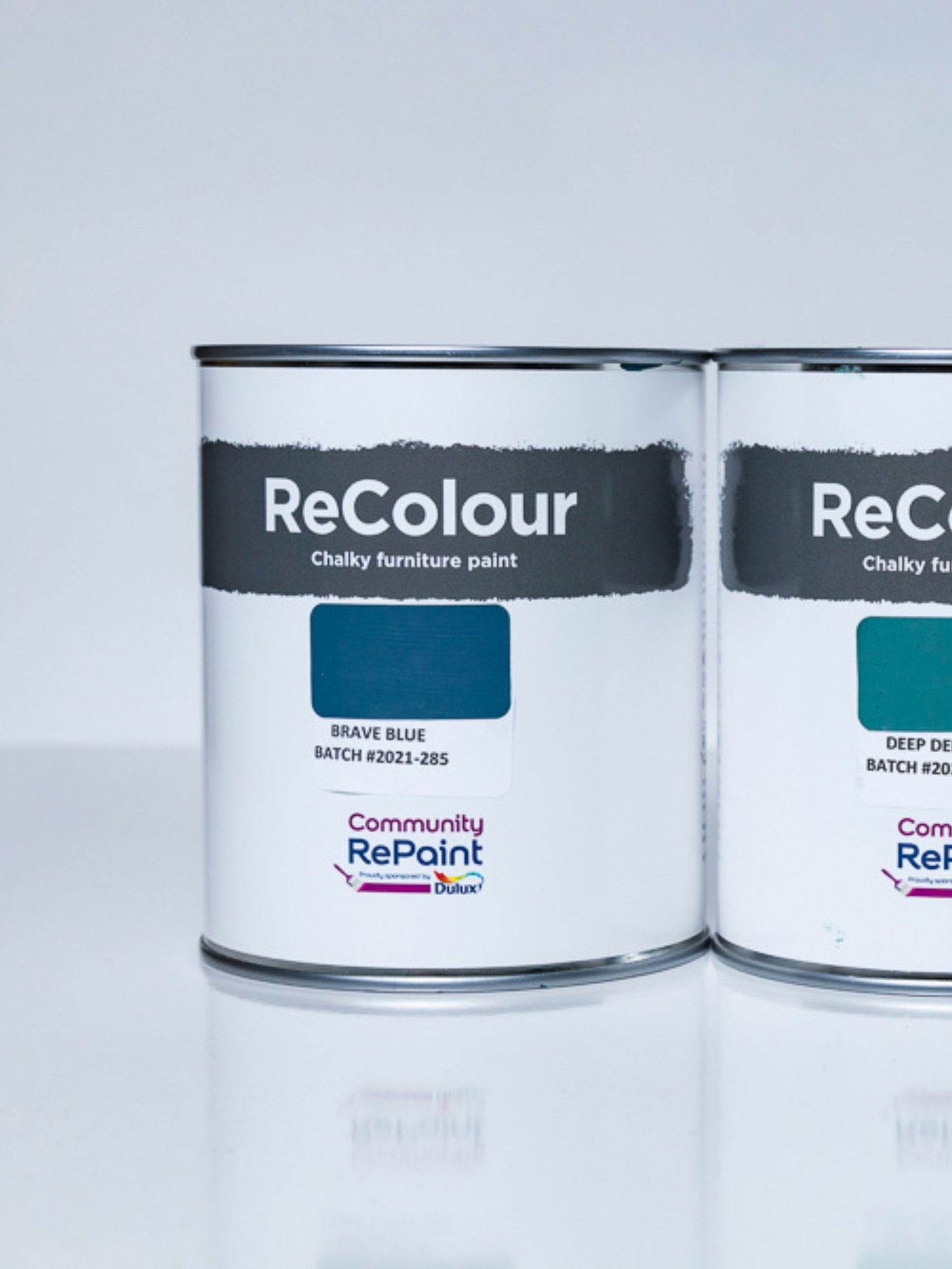 Two cans of ReColour chalky acrylic furniture paint named "Brave Blue" and "Deep Delta".