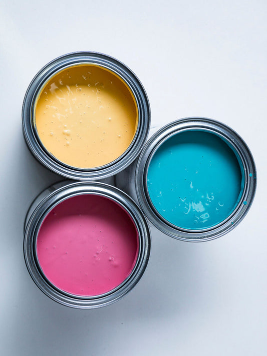 Top view of three open paint cans with yellow, blue, and pink paint inside.