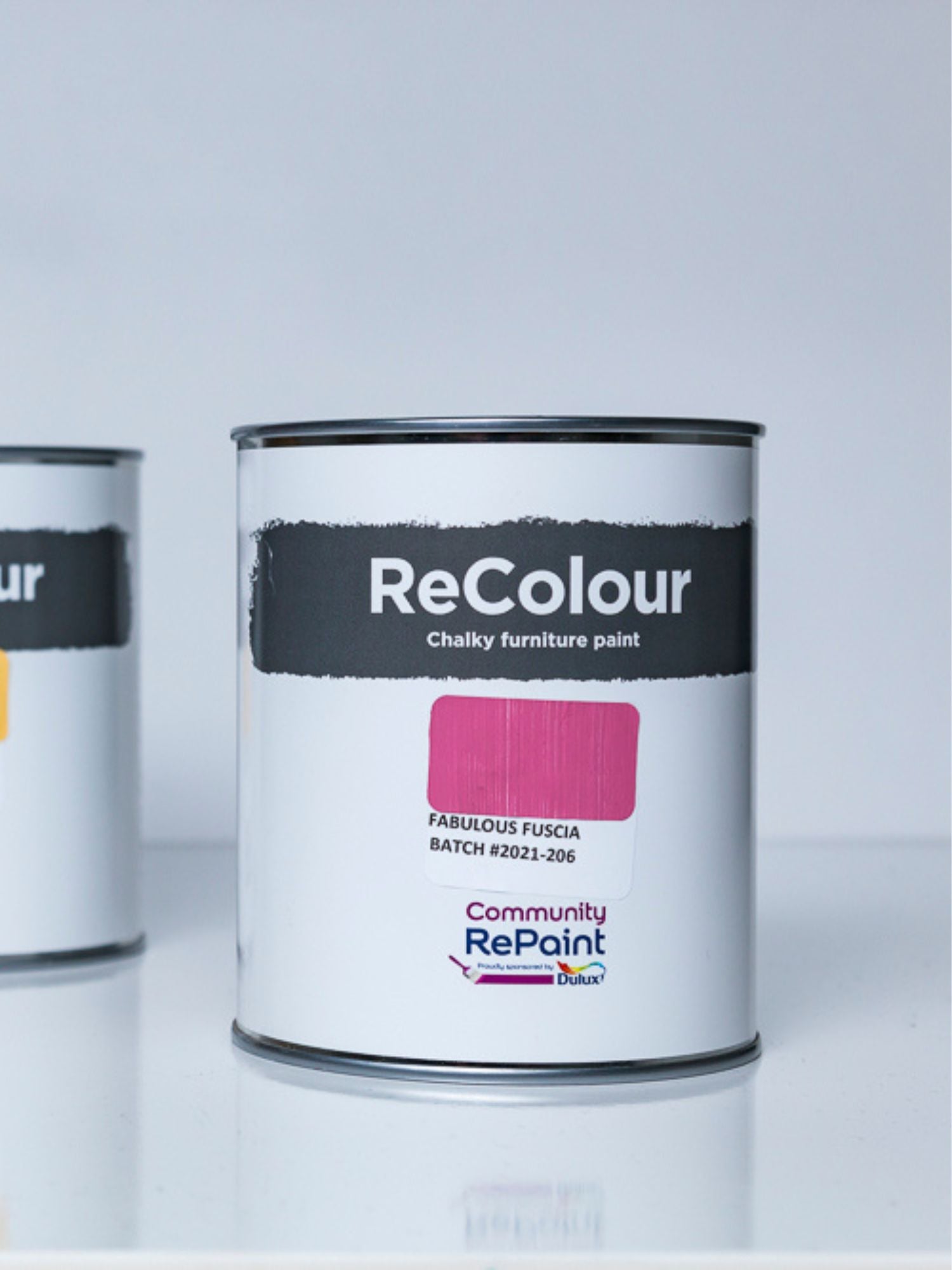 Close up of two cans of ReColour acrylic chalky furniture paint, one can paint colour named "fabulous fuscia"