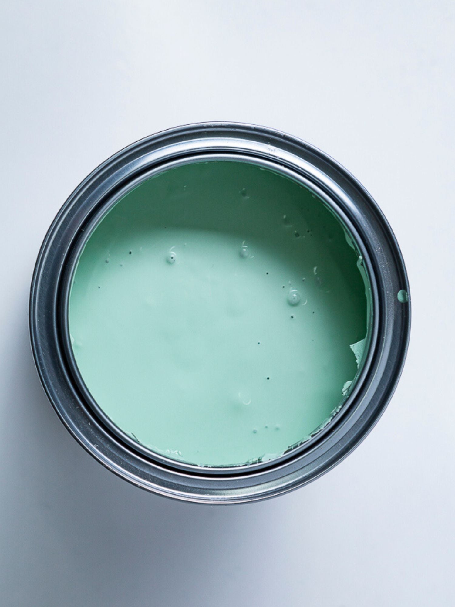 Top view of an open can of paint with a mint green colour.