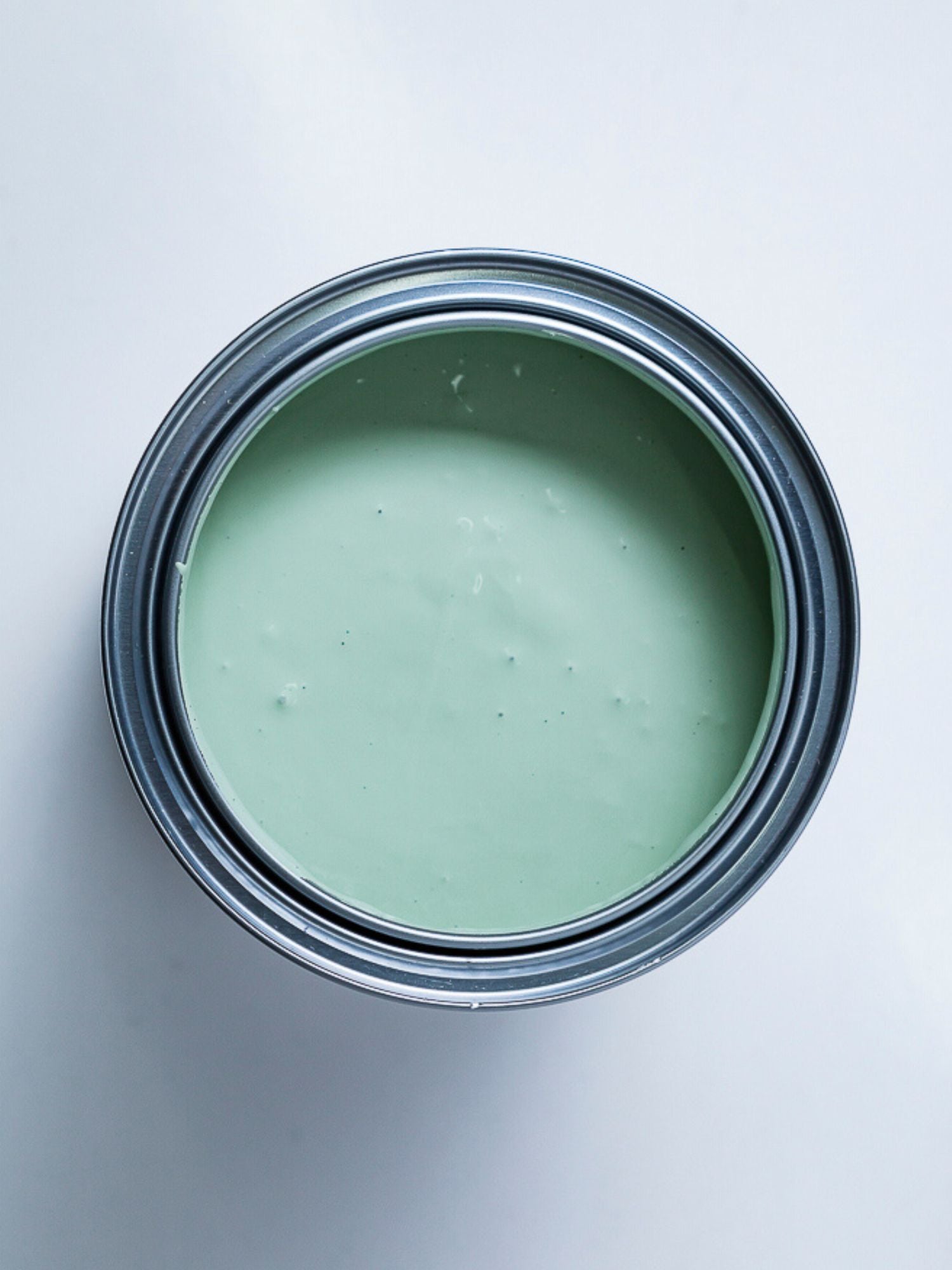 Top view of an open can of light green paint.