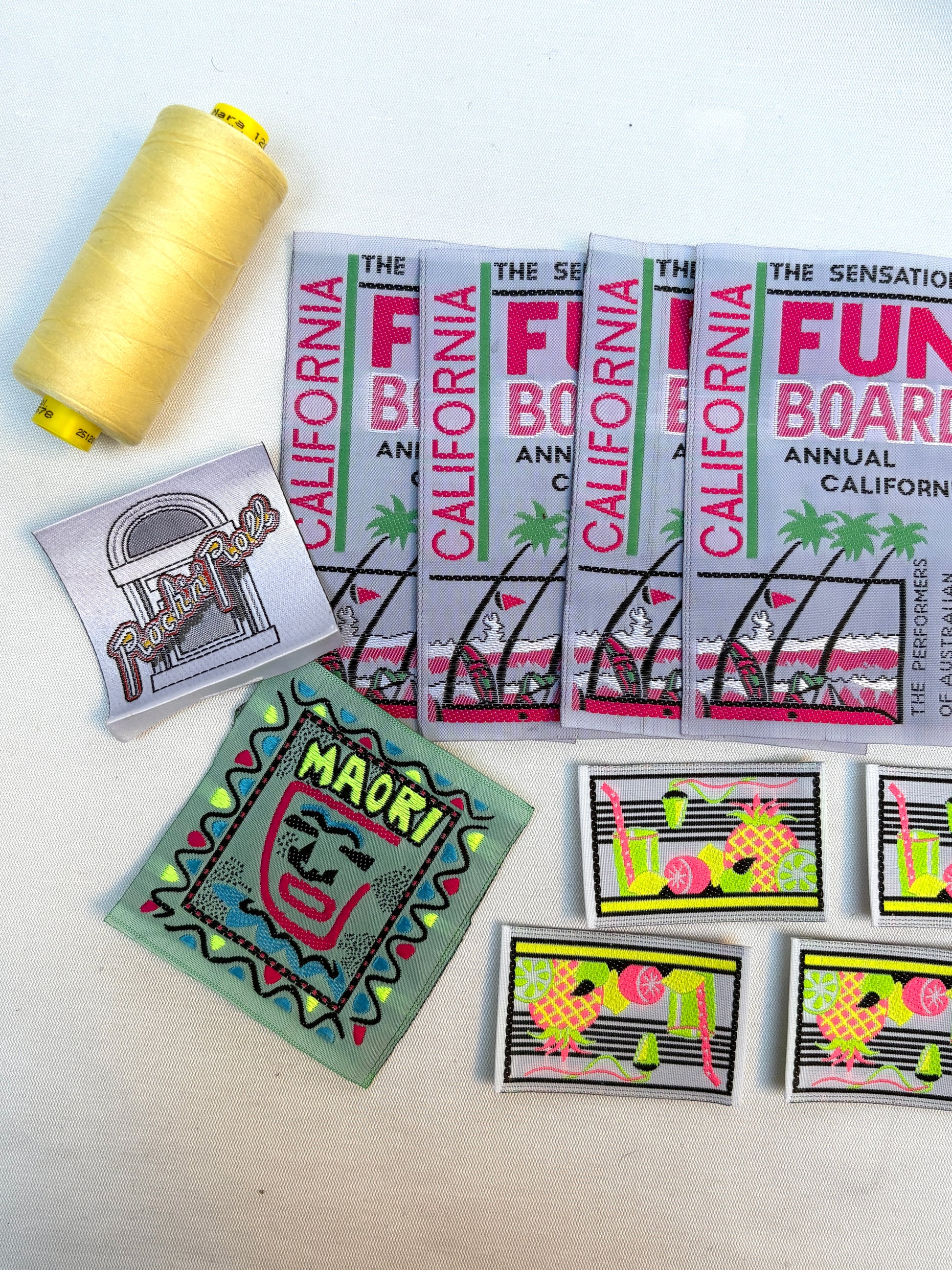 Close-up of woven labels and embroidered badges with a yellow thread spool.
