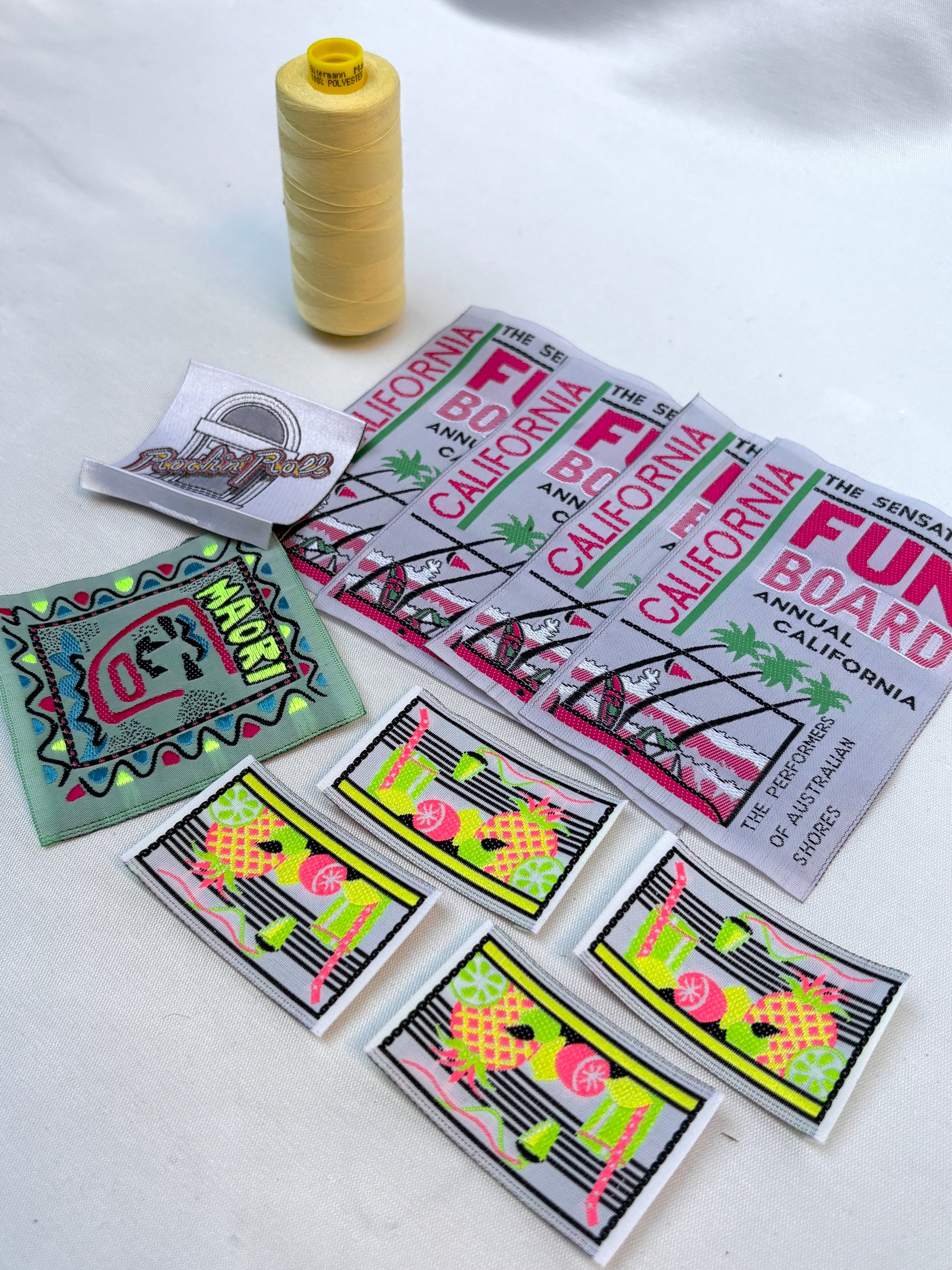 Detailed view of colourful woven labels and badges with a yellow thread spool.