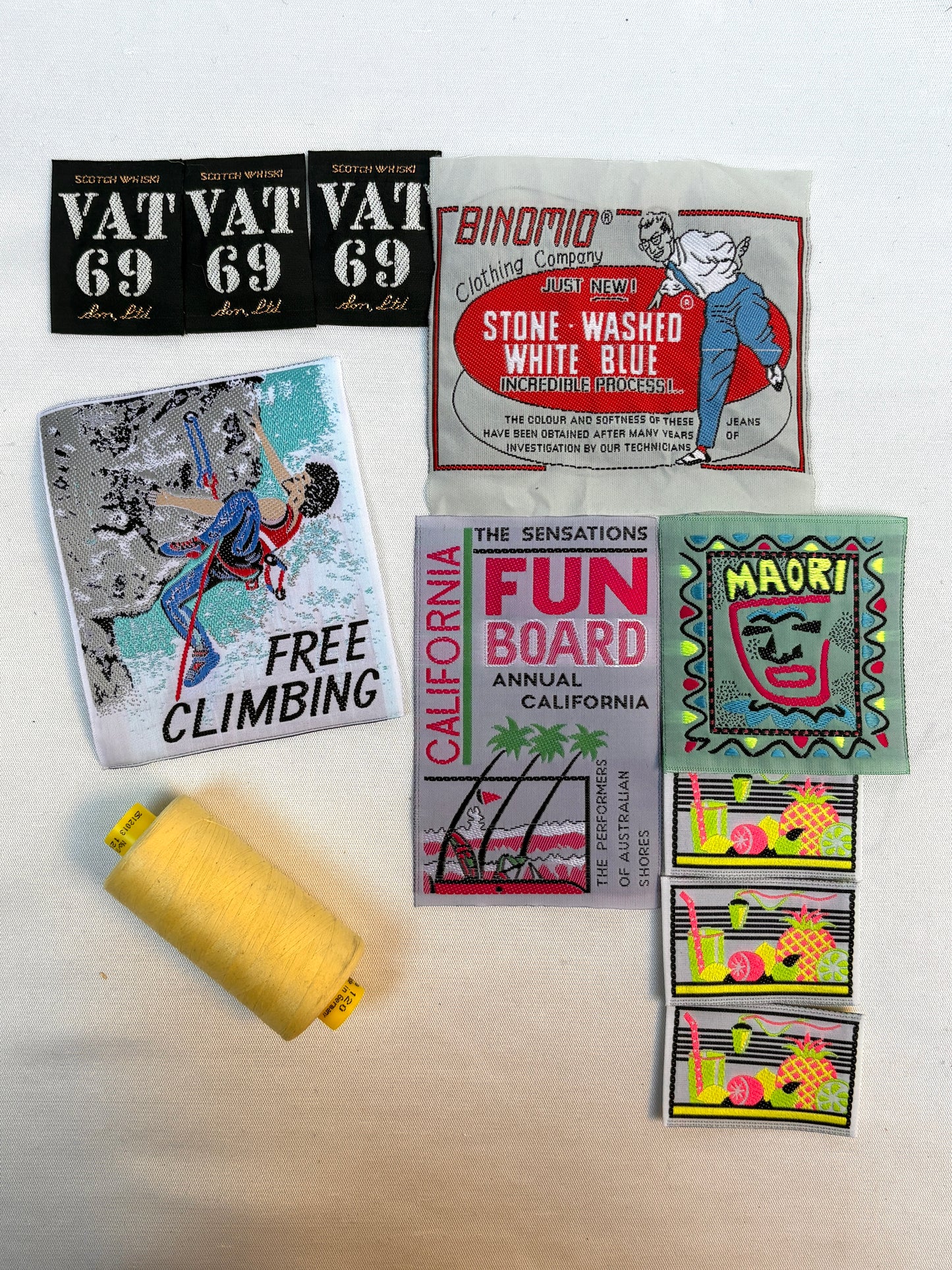 Collection of vintage-style product labels and a yellow spool on a white surface