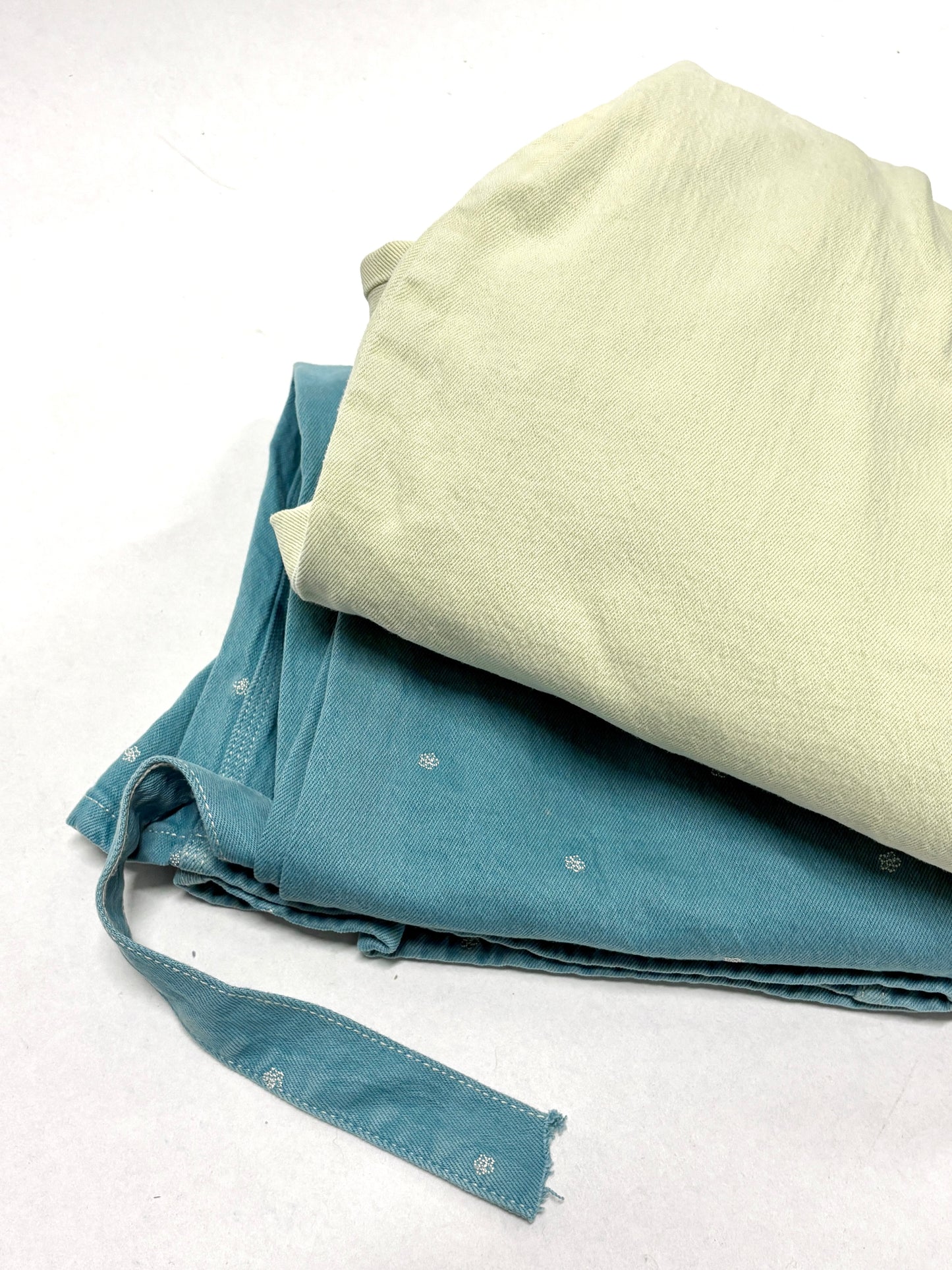 2 different types of ripped denim garments, one is light yellow in colour, and the other is light green