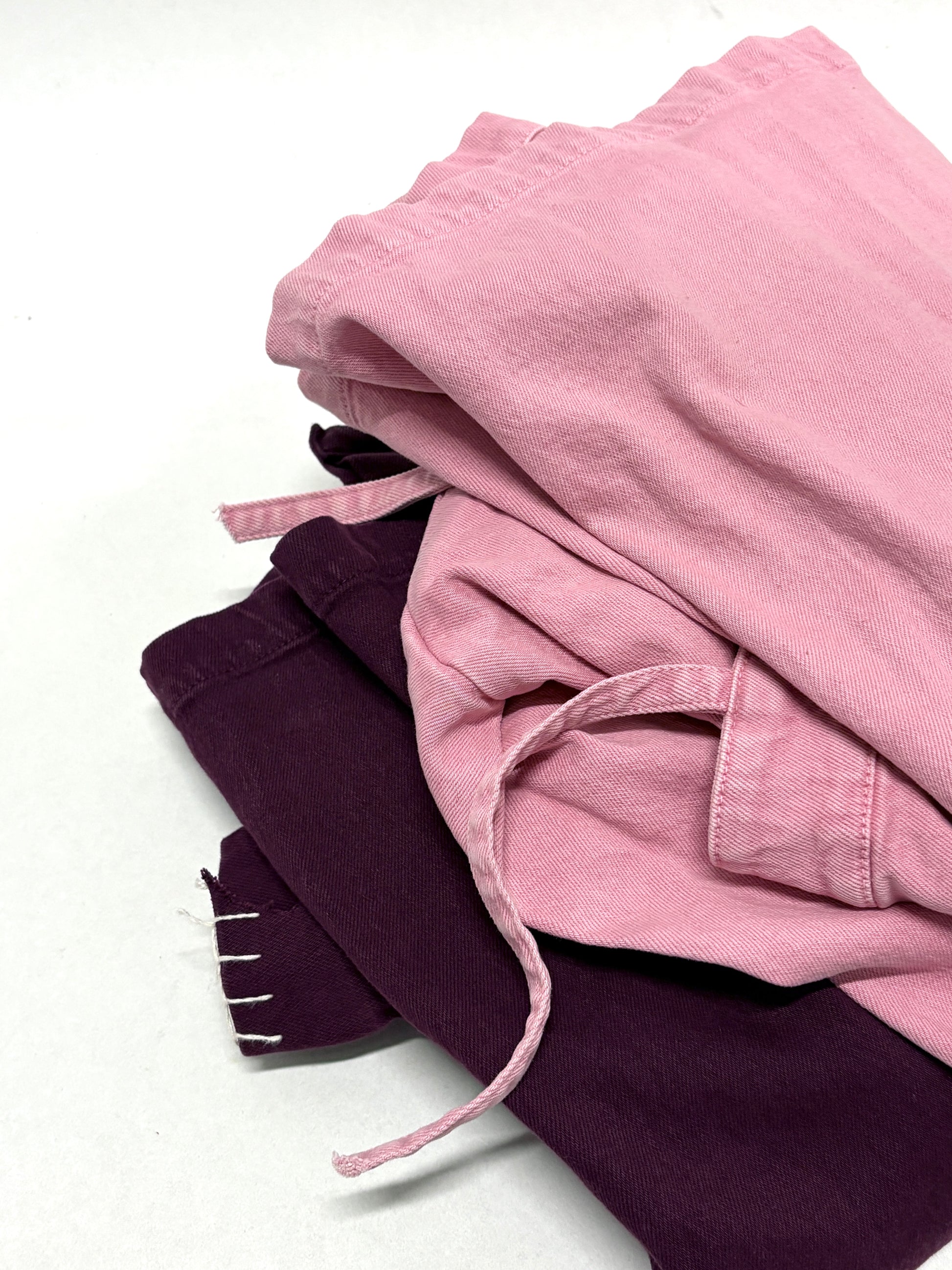 2 different types of ripped denim garments, one is pink in colour, and the other is purple