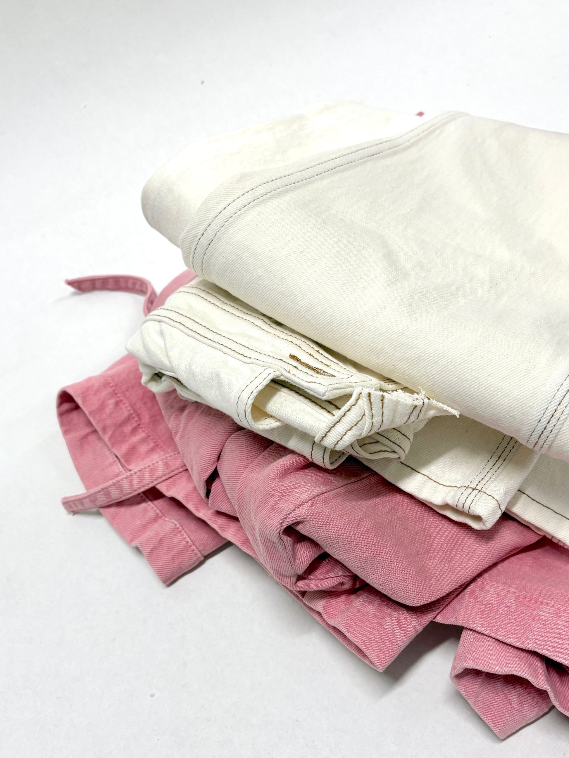 2 different types of ripped denim garments, one is white in colour, and the other is pink