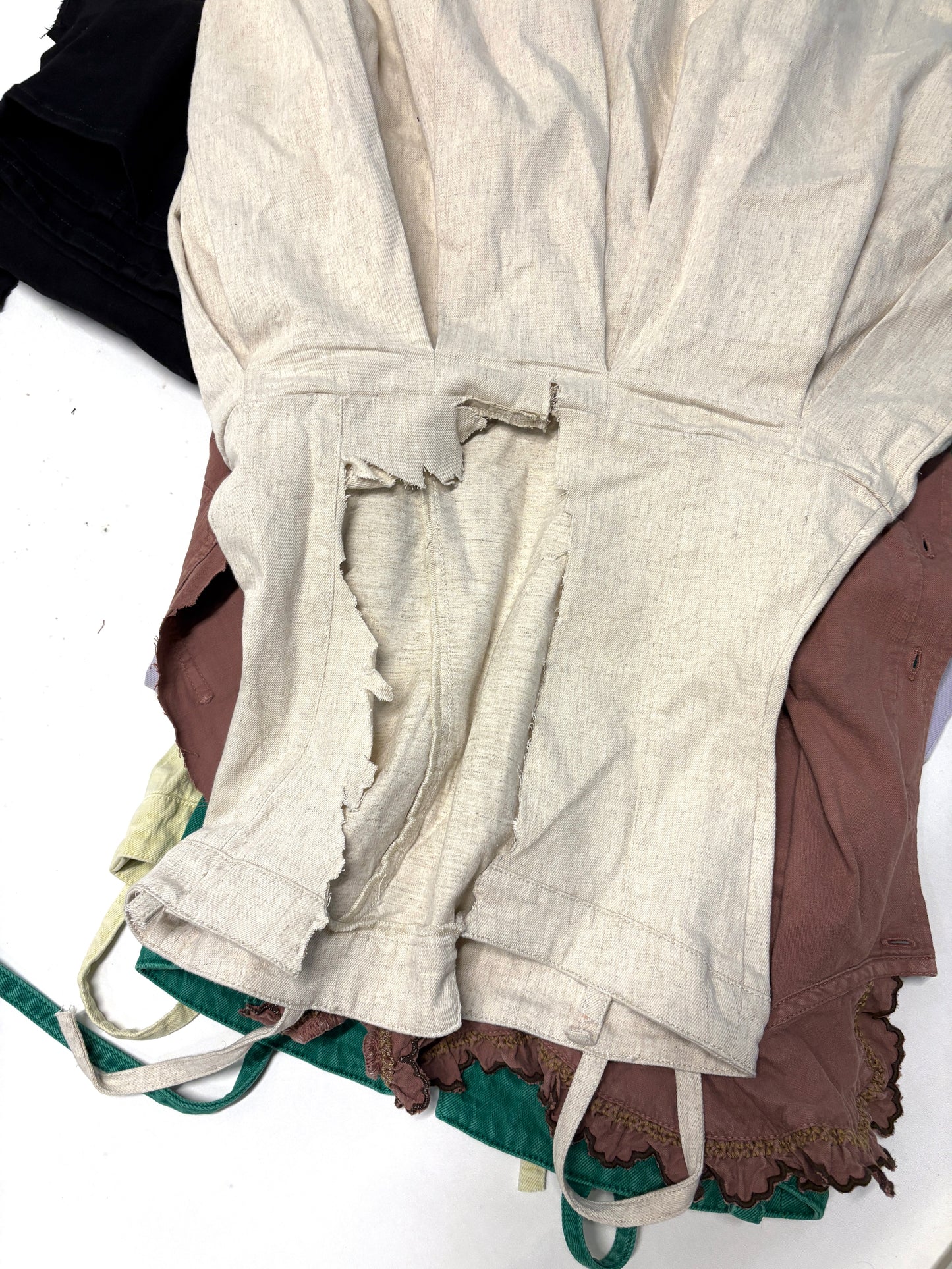 White ripped denim garment on top of brown ripped denim garment 