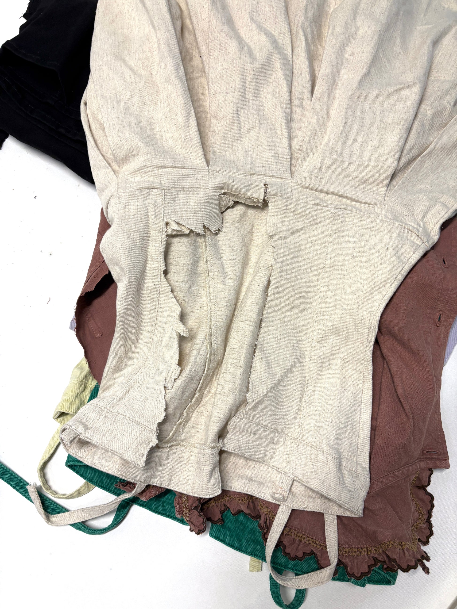 White ripped denim garment on top of brown ripped denim garment 