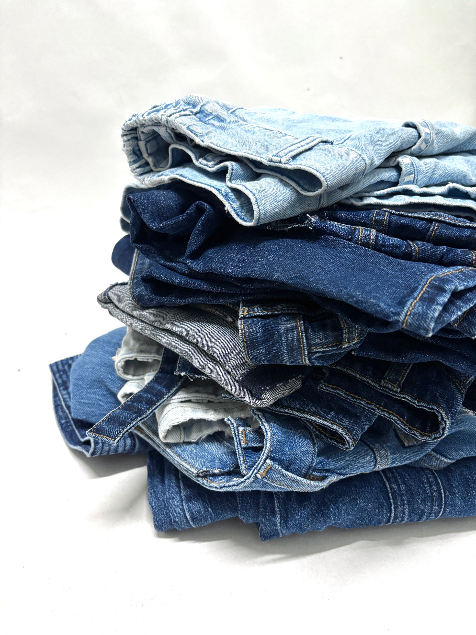 Stack of folded blue ripped denim garments 
