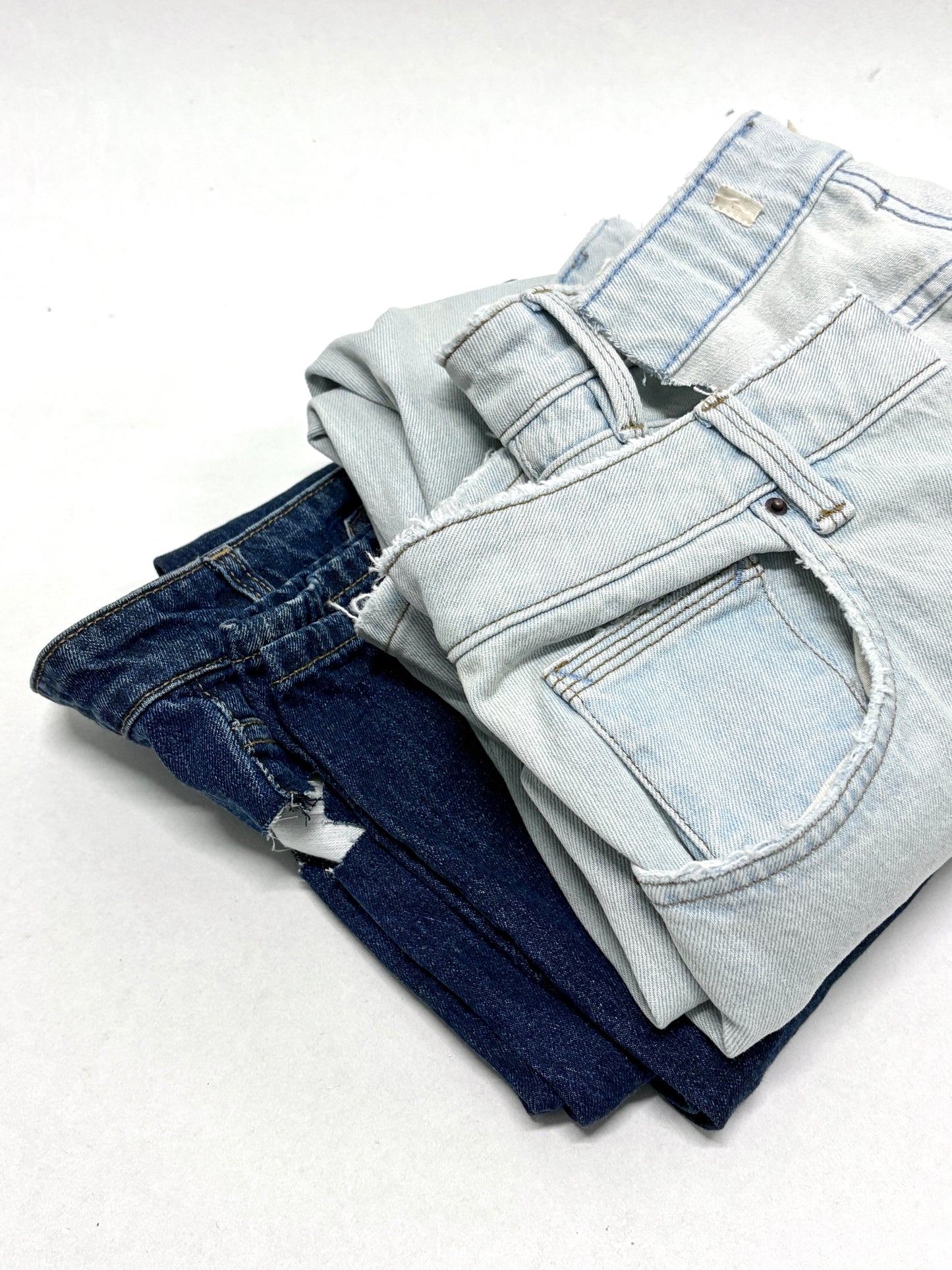 2 folded, ripped denim garments, light blue and navy 