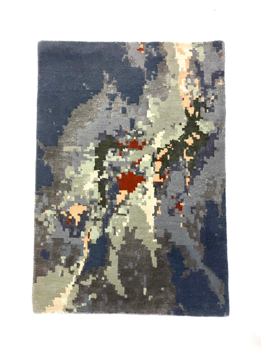 A hand knotted Cascade rug with a geometric pattern in shades of blue, gray, and red