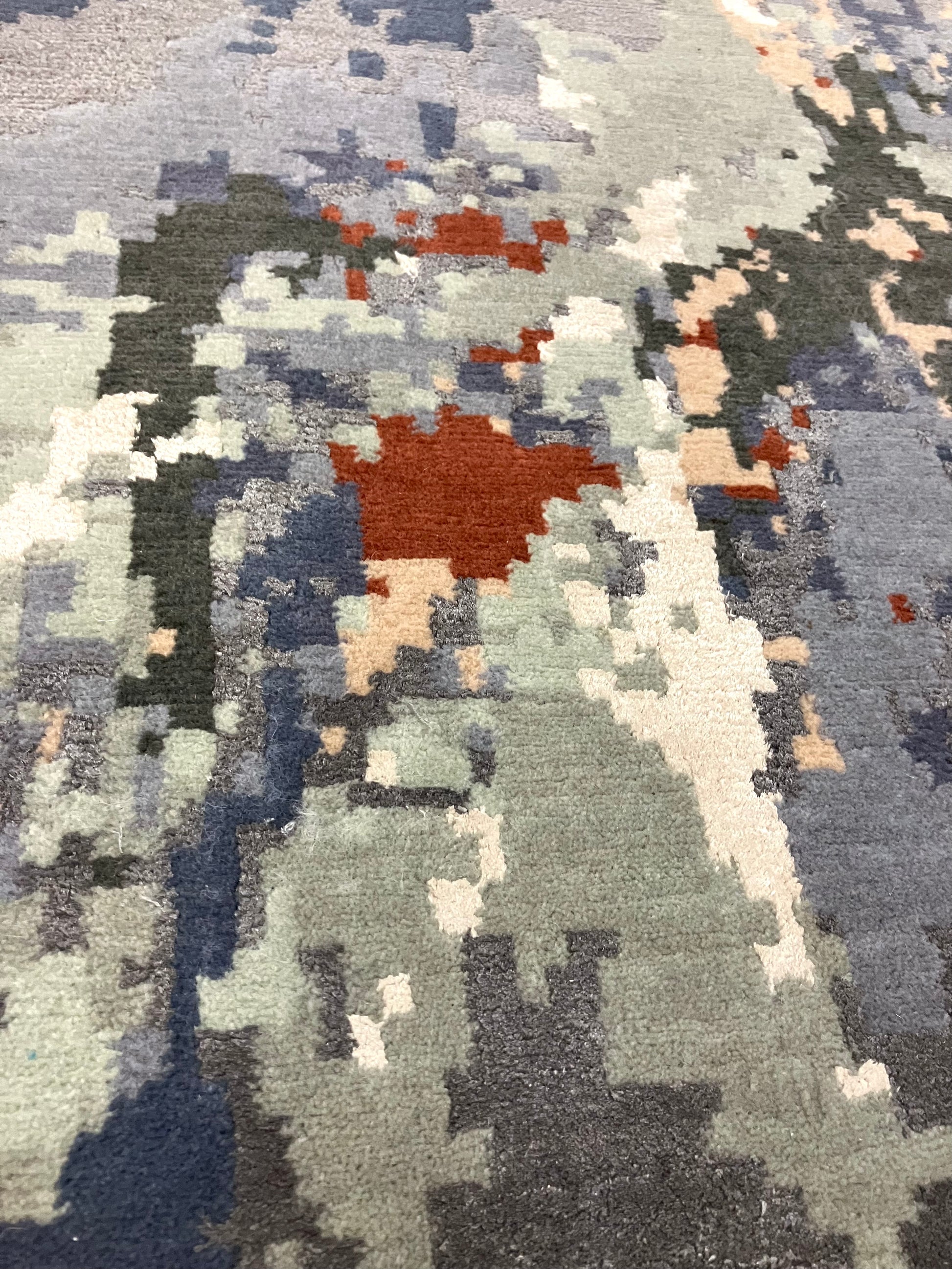Close-up of a hand knotted Cascade rug with a geometric pattern in shades of blue, gray, and red