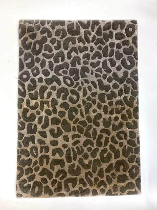A rectangular, hand knotted wool rug with a leopard animal print pattern in shades of brown and beige.