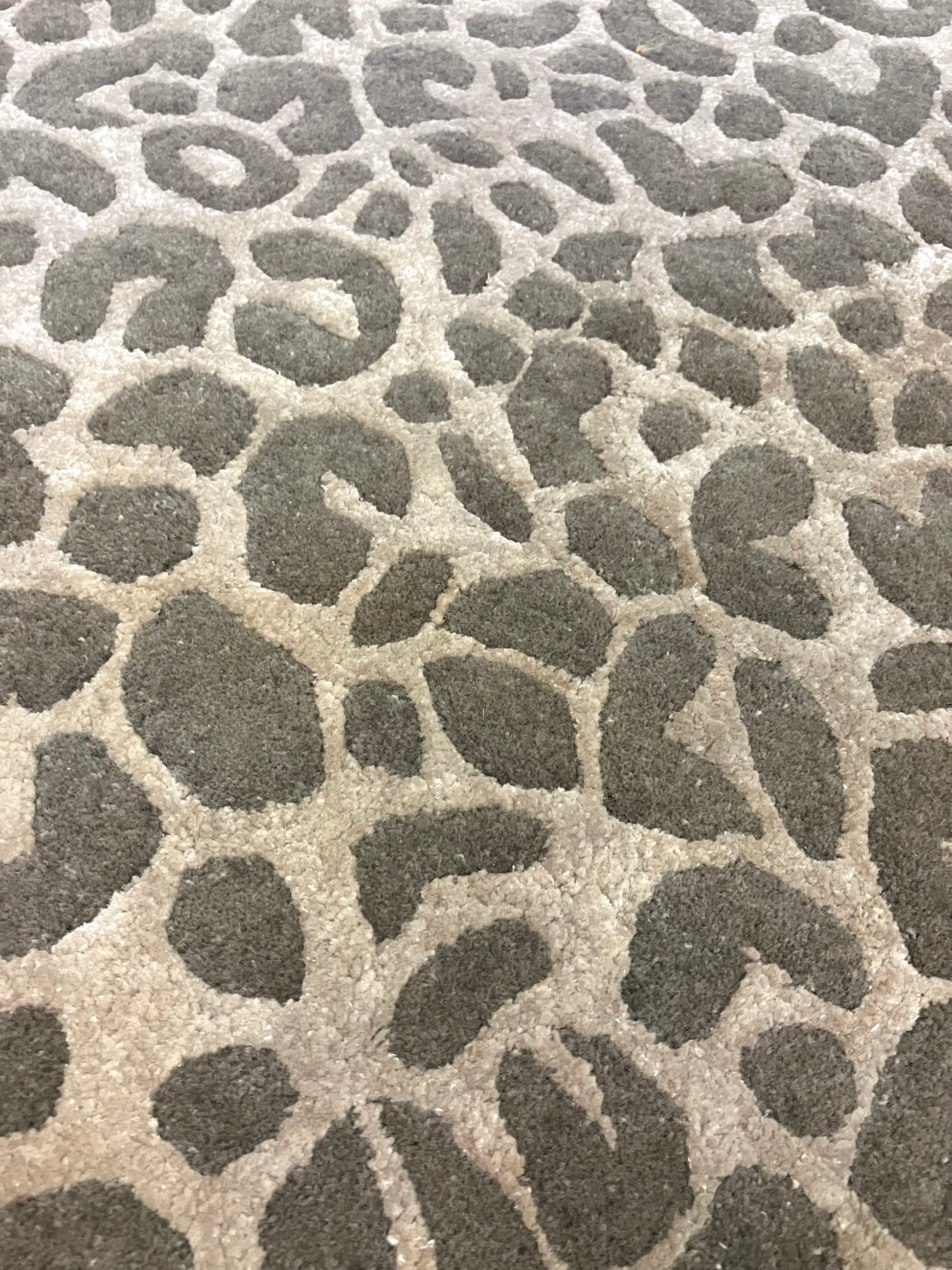 Close-up of a rectangular, hand knotted wool rug with a leopard animal print pattern in shades of brown and beige.