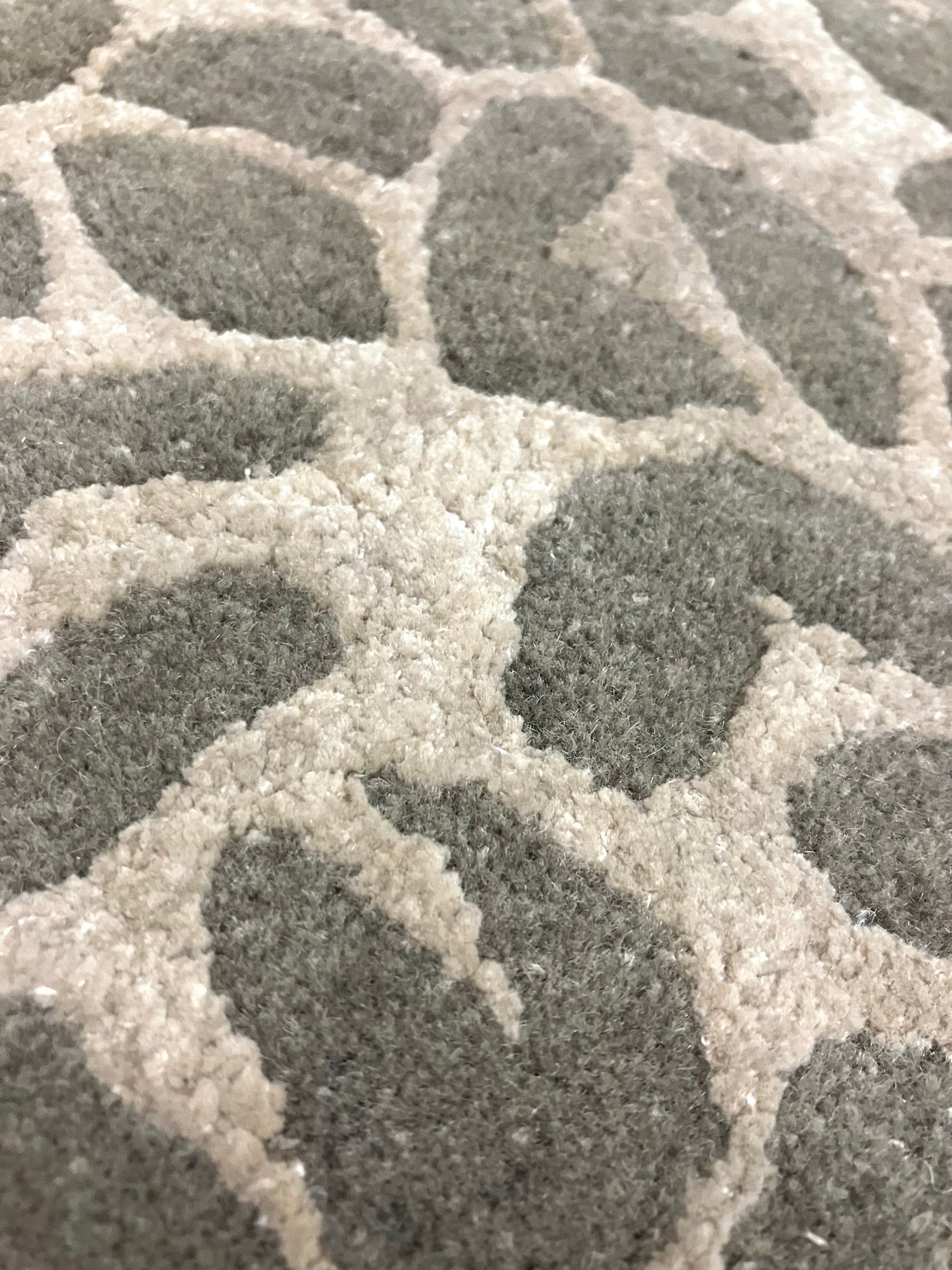 Close-up of a rectangular, hand knotted wool rug with a leopard animal print pattern in shades of brown and beige.