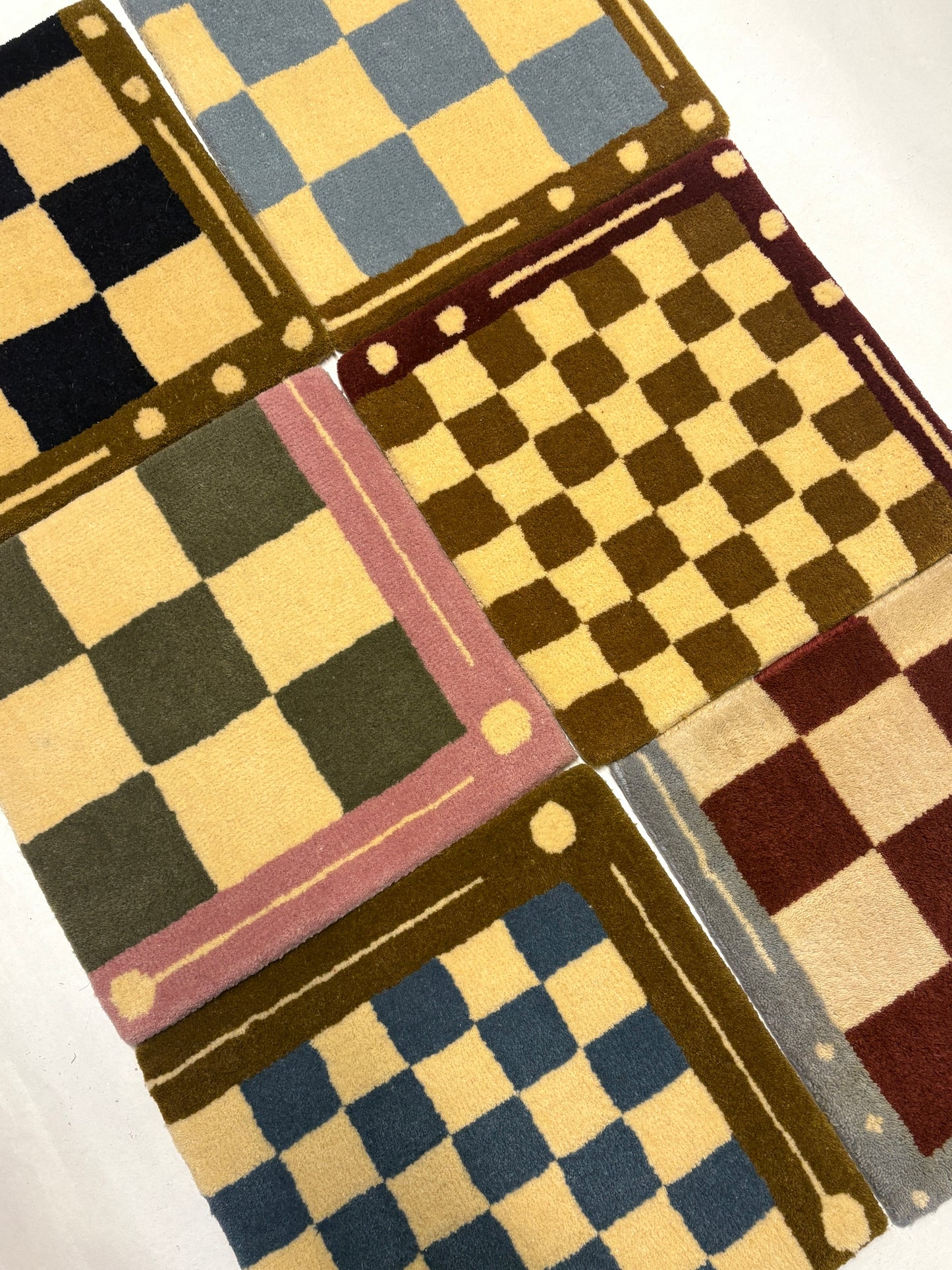 6 different colours of square/jack patterned rug samples.