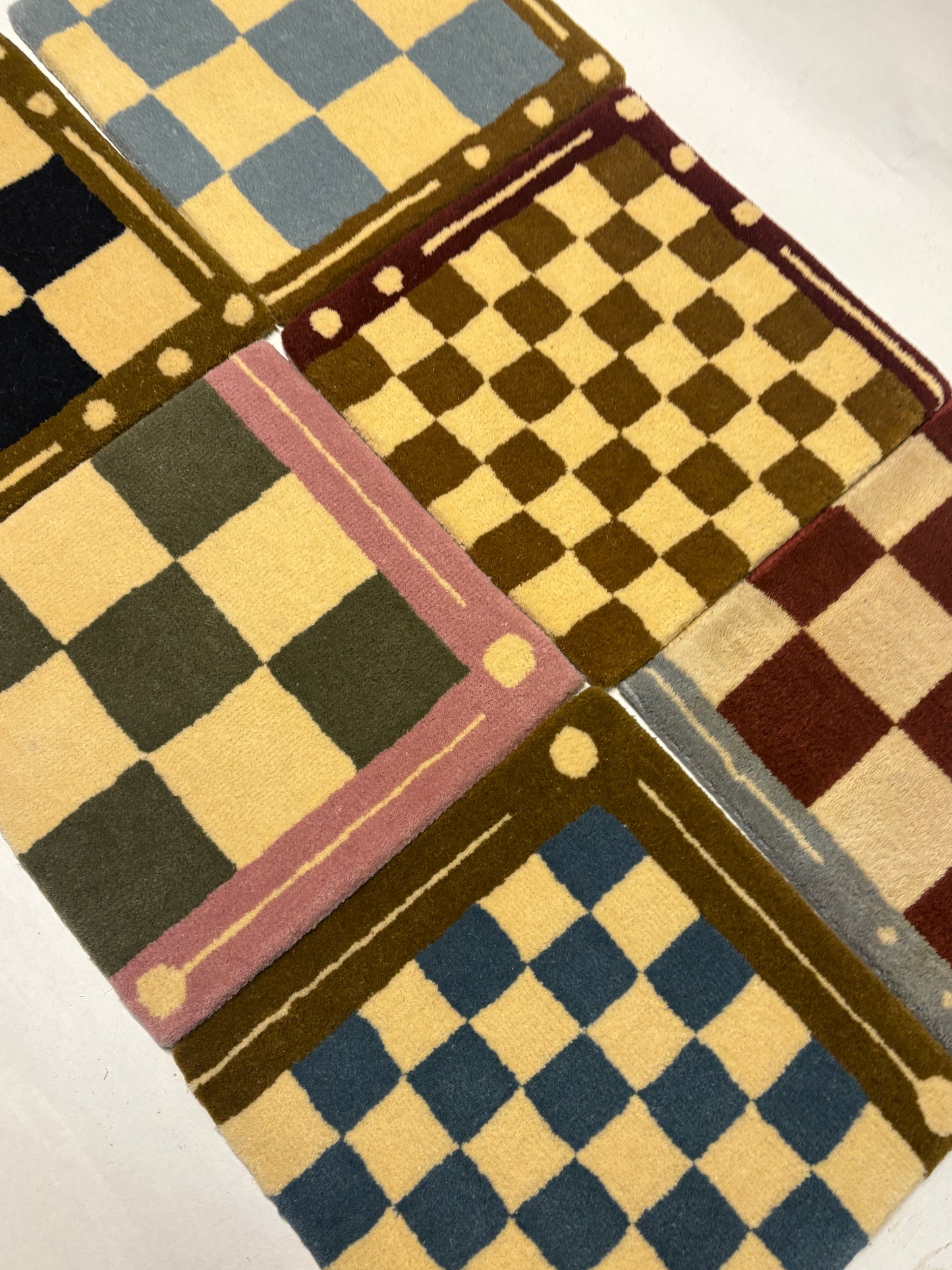 6 different colours of square/jack patterned rug samples.