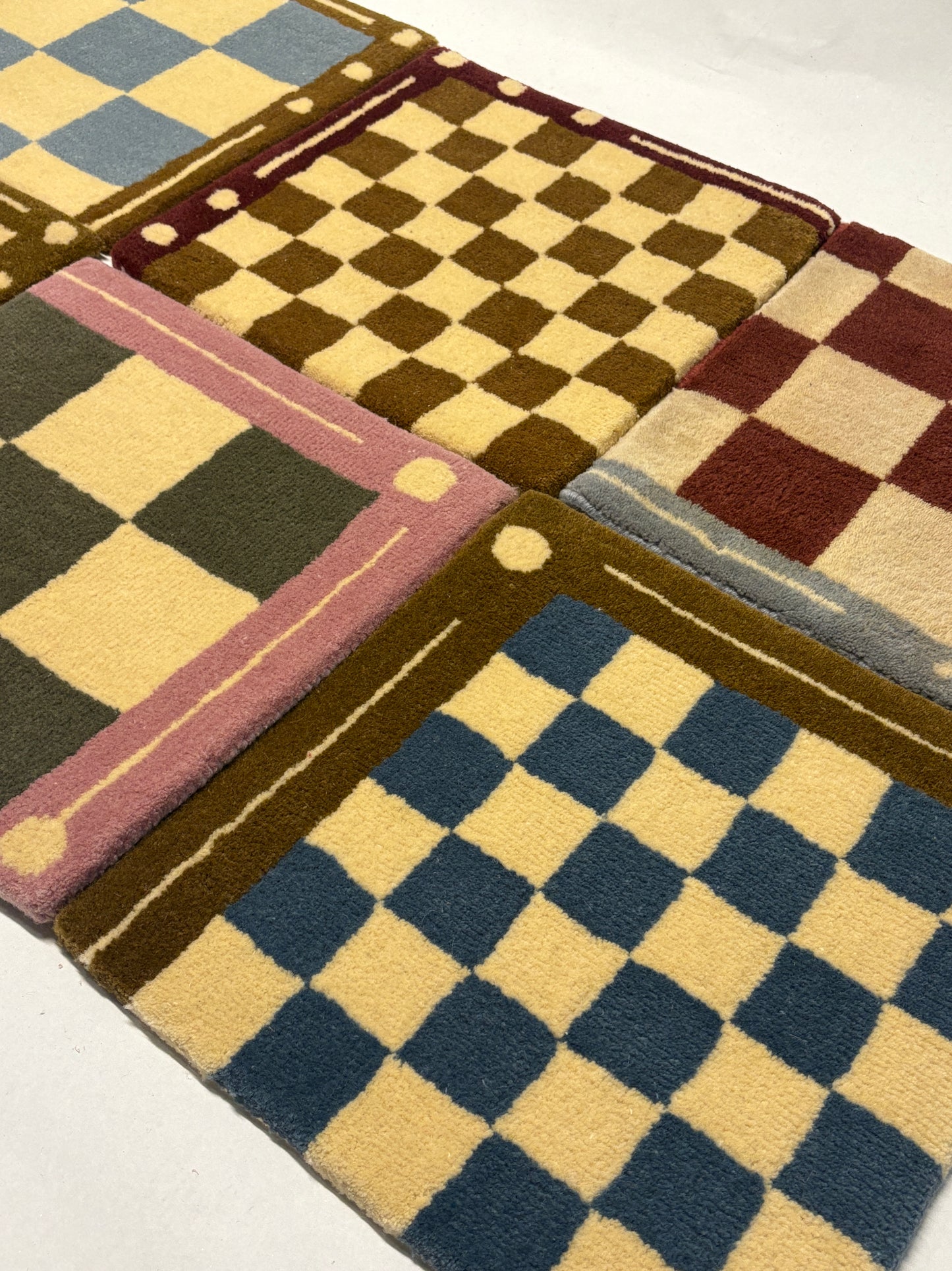 Close-up of 6 different colours of square/jack patterned rug samples.