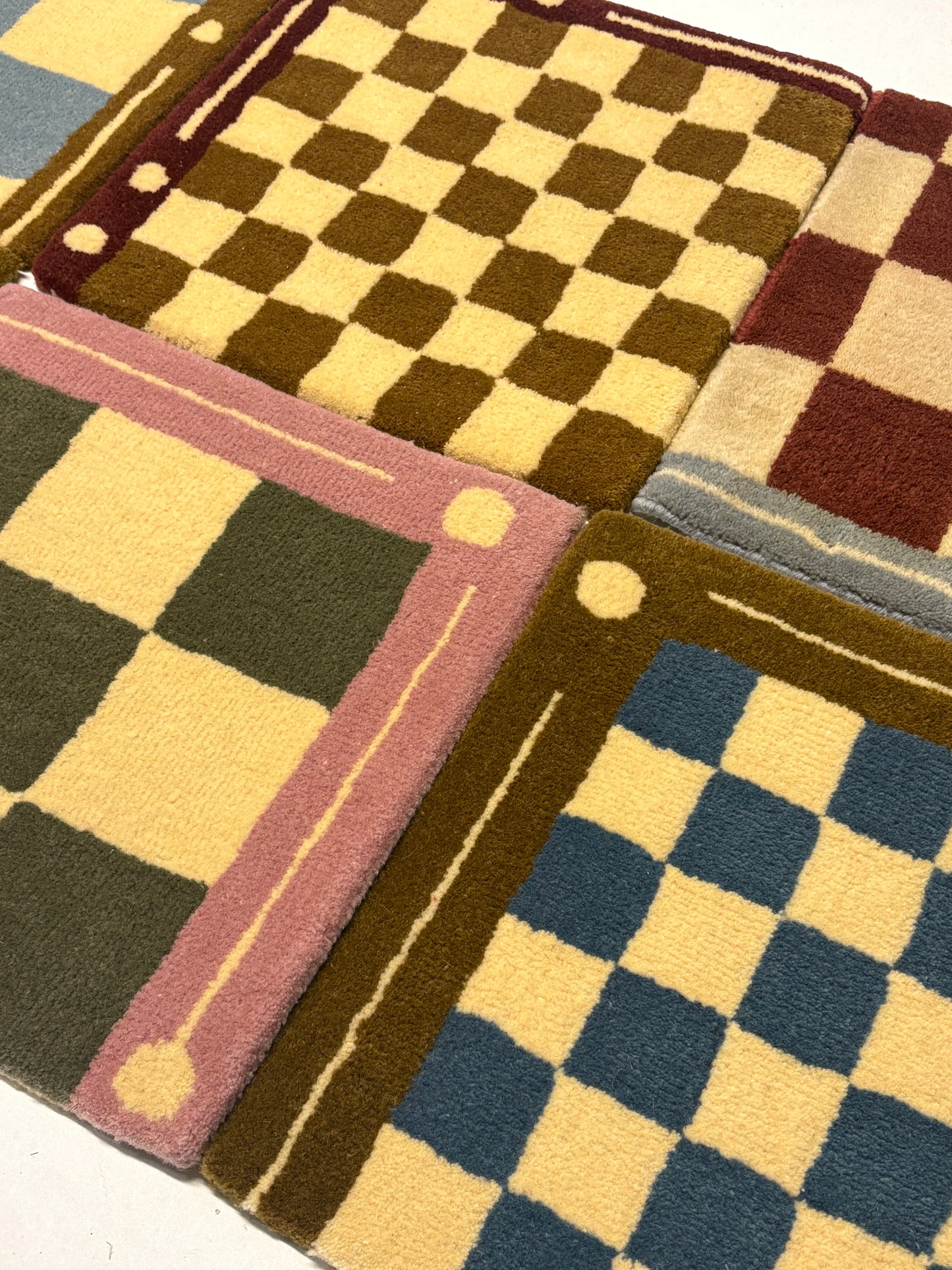 Close-up of 4 different colours of square/jack patterned rug samples.