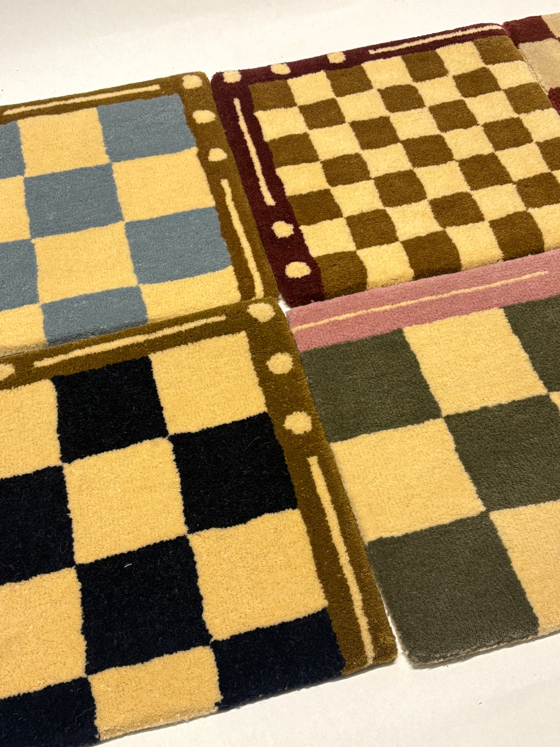 4 different colours of square/jack patterned rug samples.