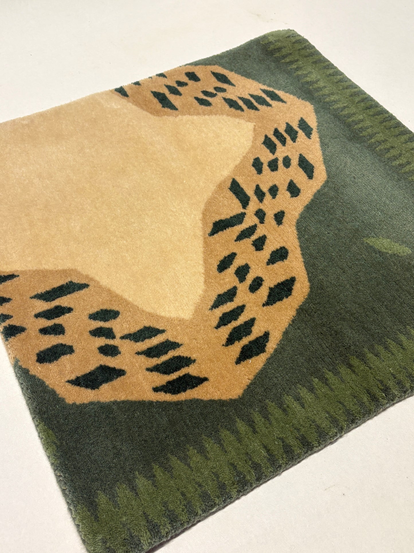 Green and beige coloured geometric patterned rug sample