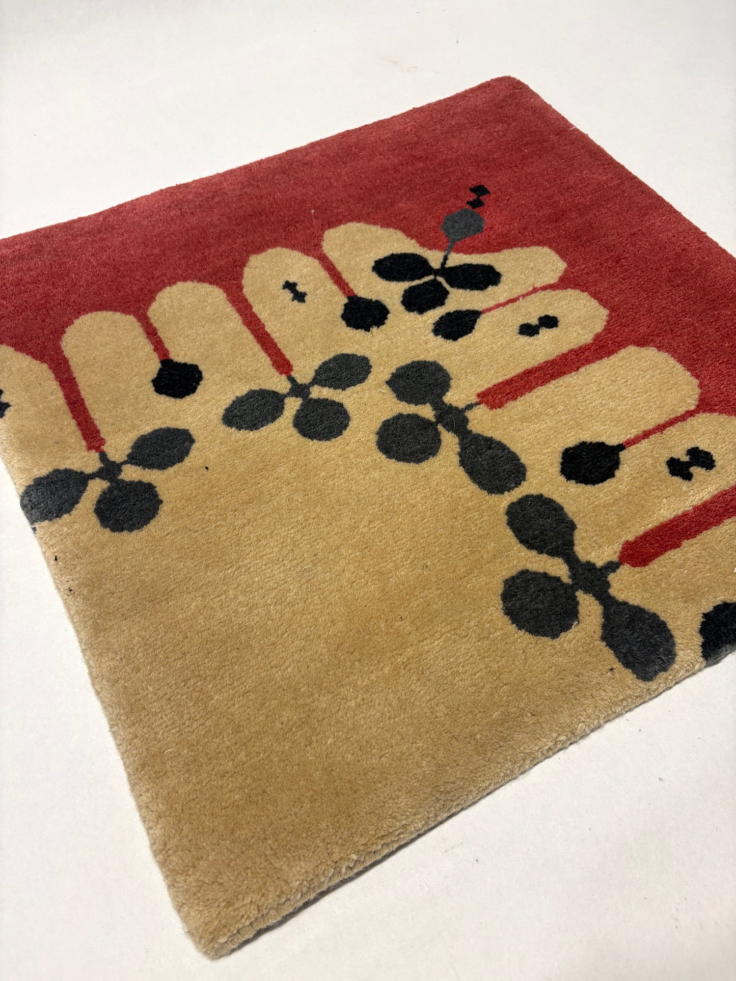 Beige, red, grey, and black geometric patterned rug sample