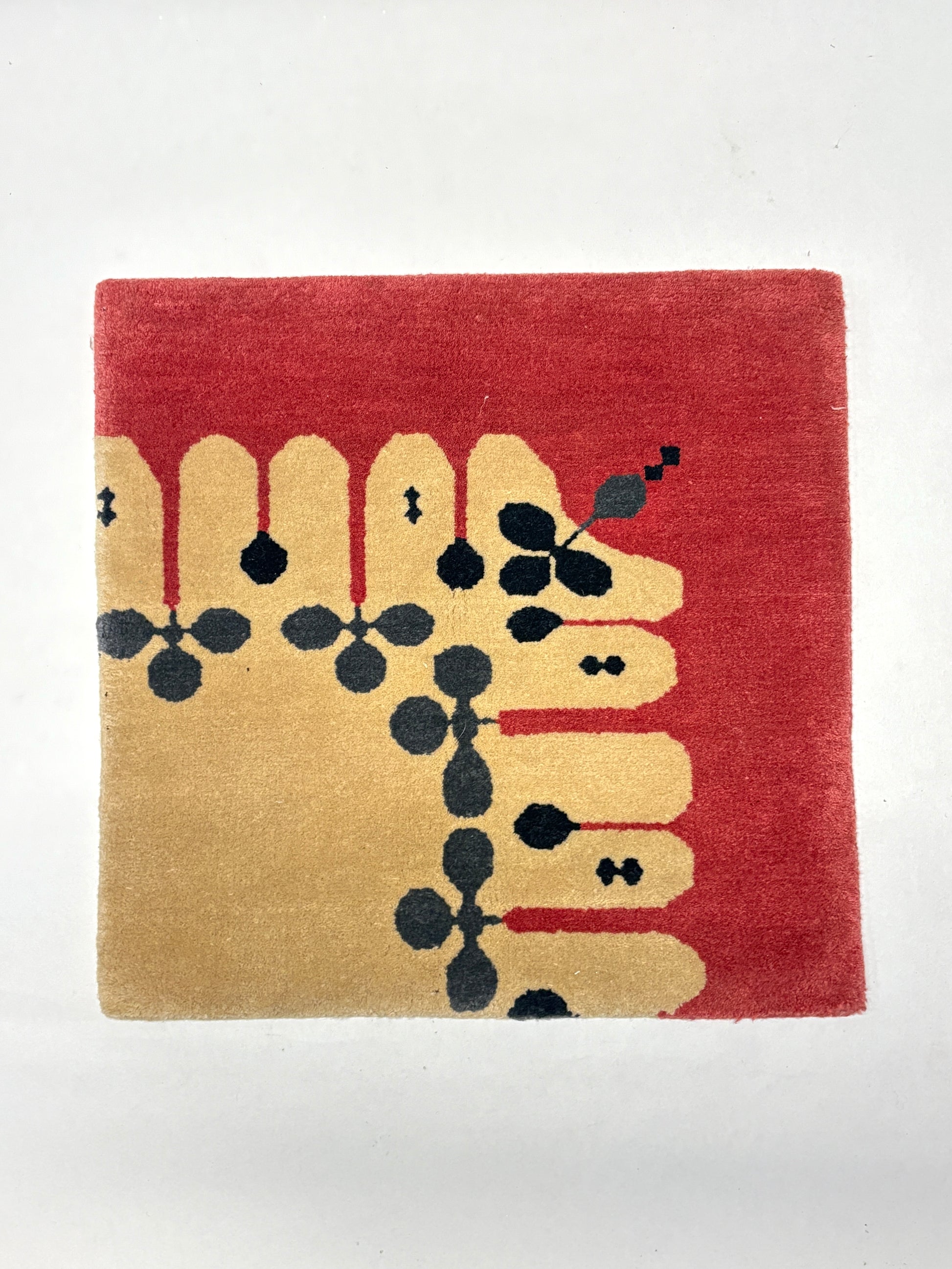 Beige, red, grey, and black geometric patterned rug sample