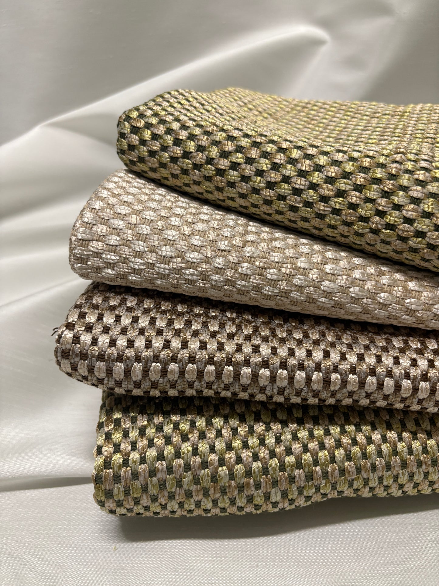 Close-up of stacked woven fabric swatches in soft neutral tones.