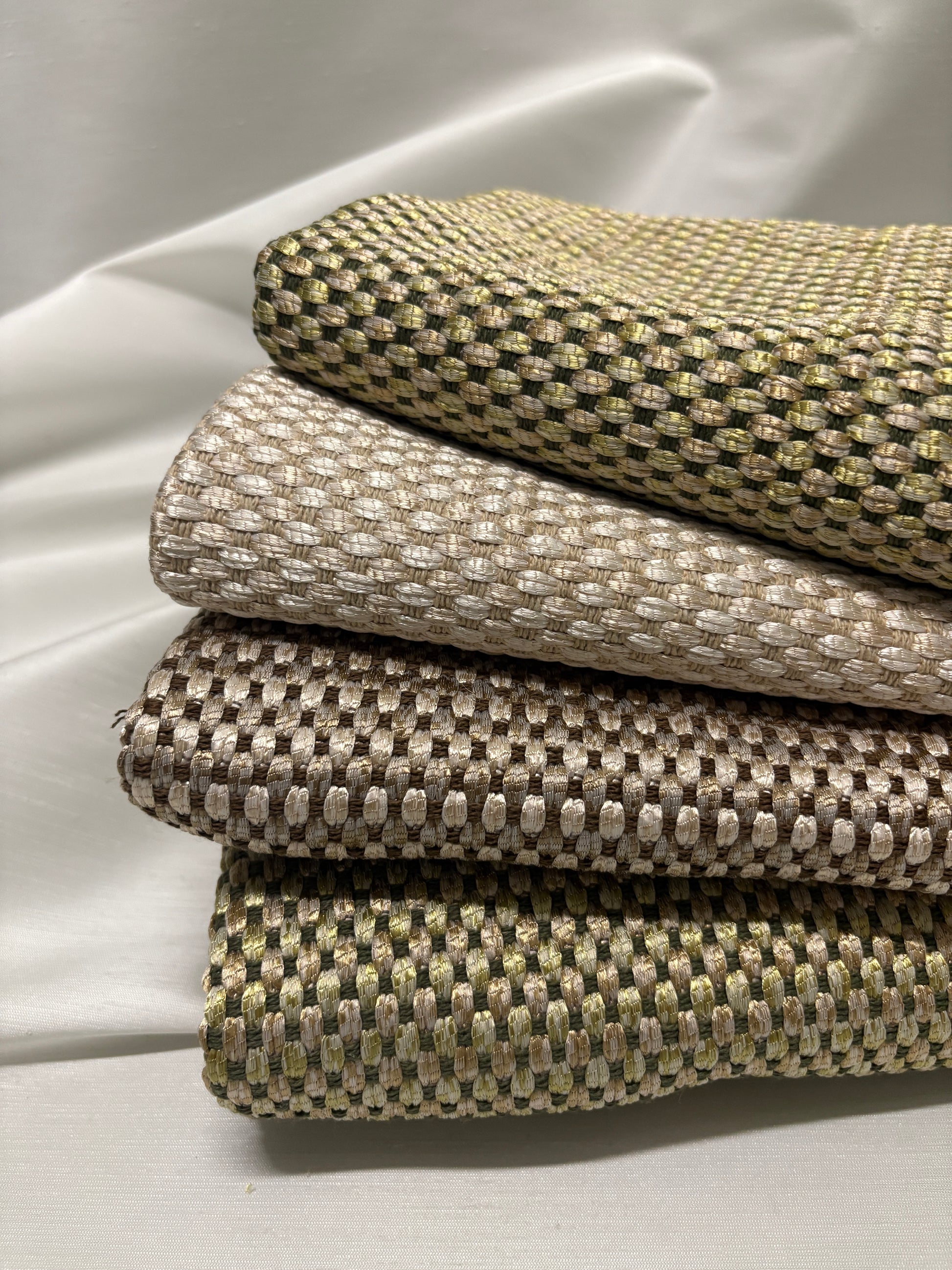 Close-up of stacked woven fabric swatches in soft neutral tones.