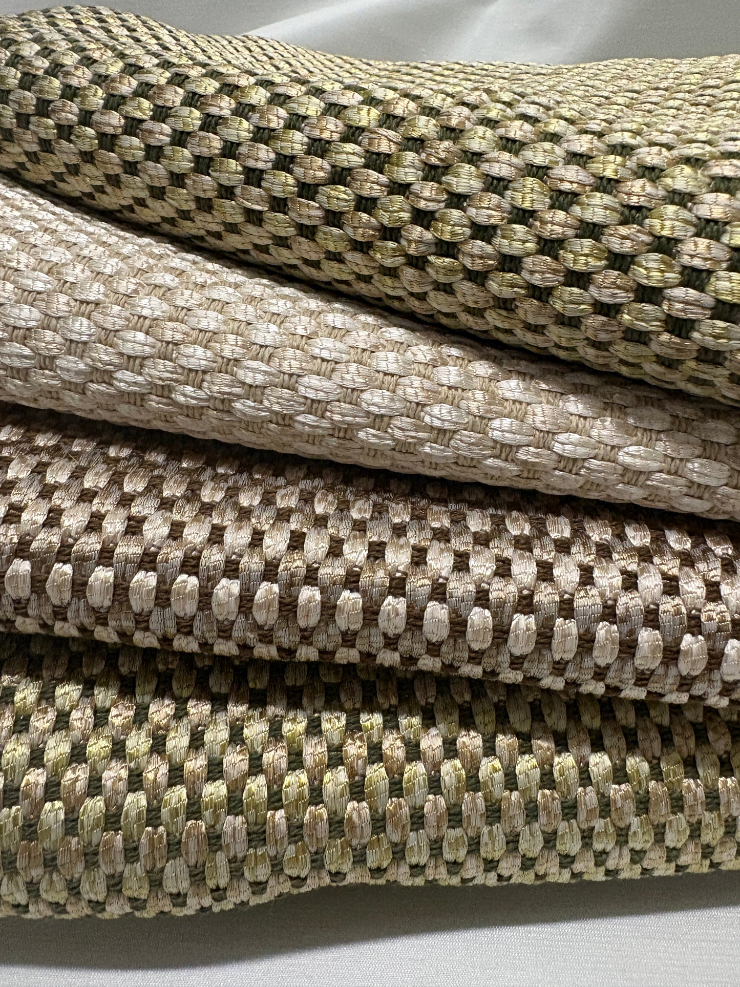 Detailed view of stacked woven fabric swatches in soft neutral shades.