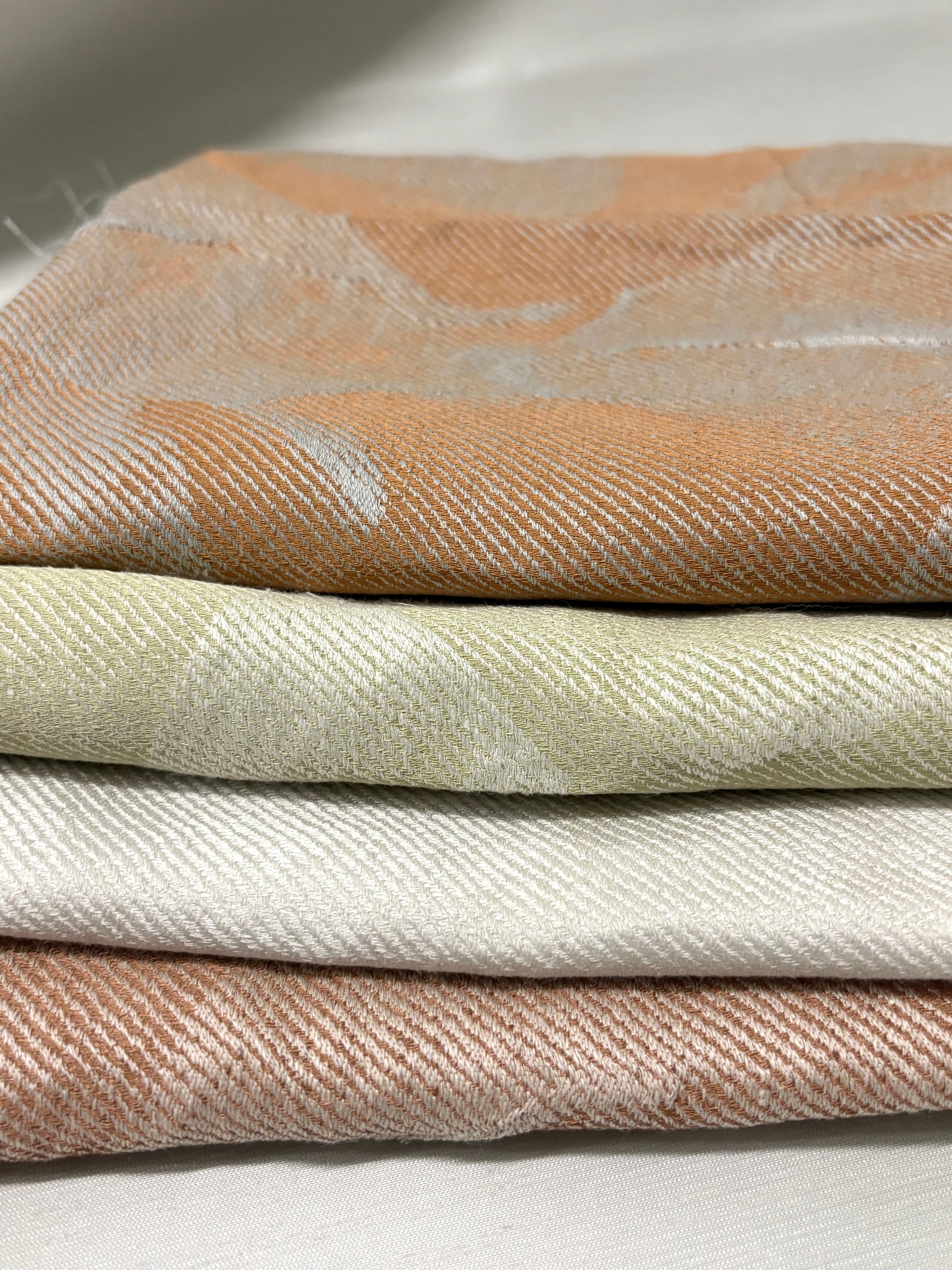 Close-up of a hand holding stacked neutral fabric swatches.