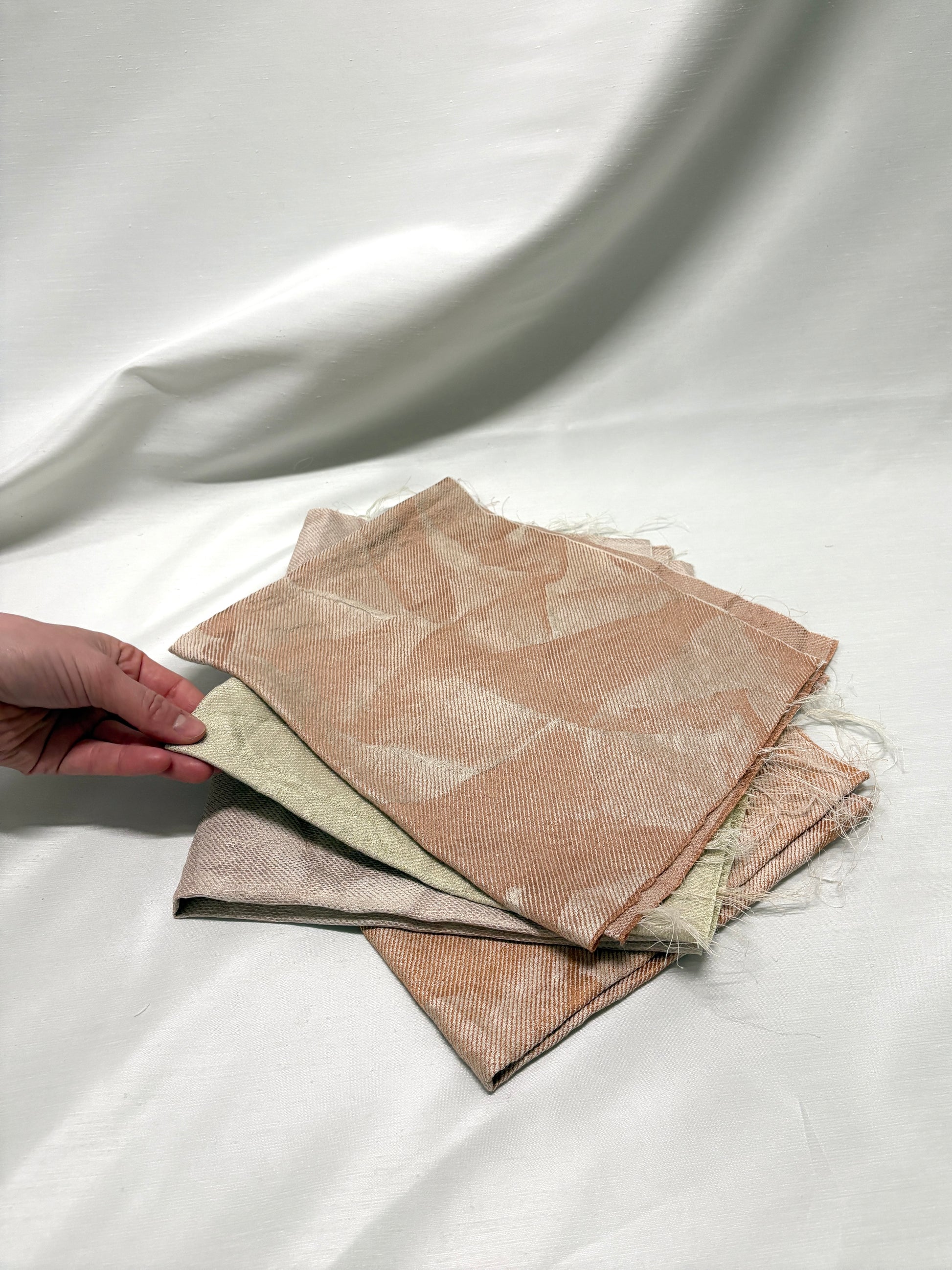 Close-up of a hand holding layered neutral fabric swatches.