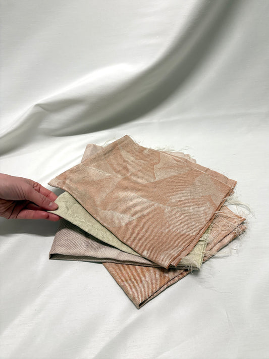 Close-up of a hand holding layered neutral fabric swatches.