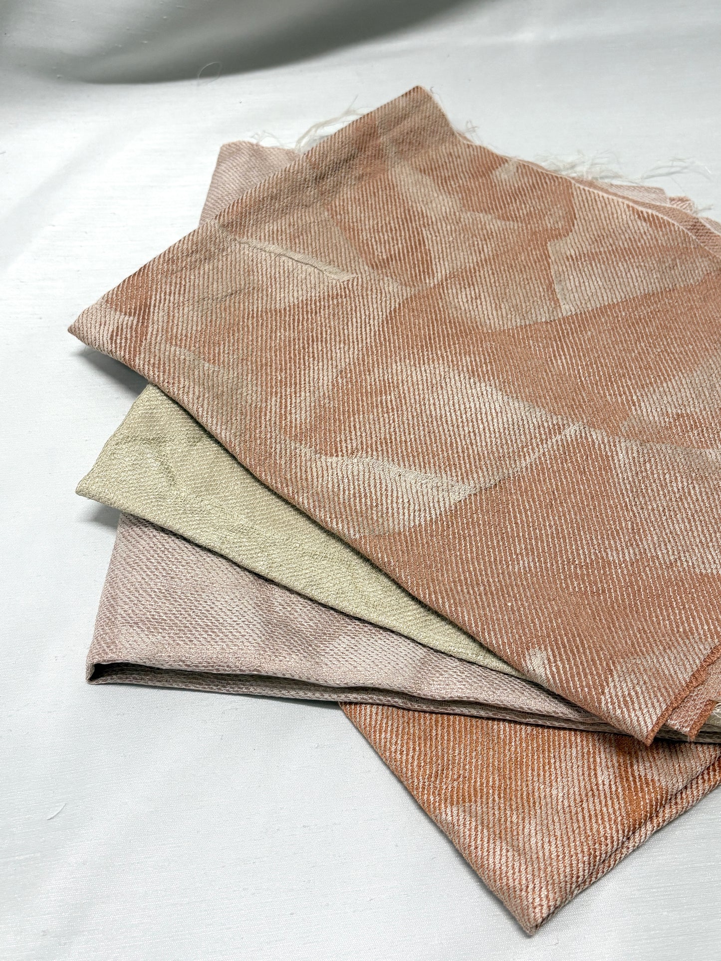 Close-up of layered neutral fabric swatches in soft beige and green tones.